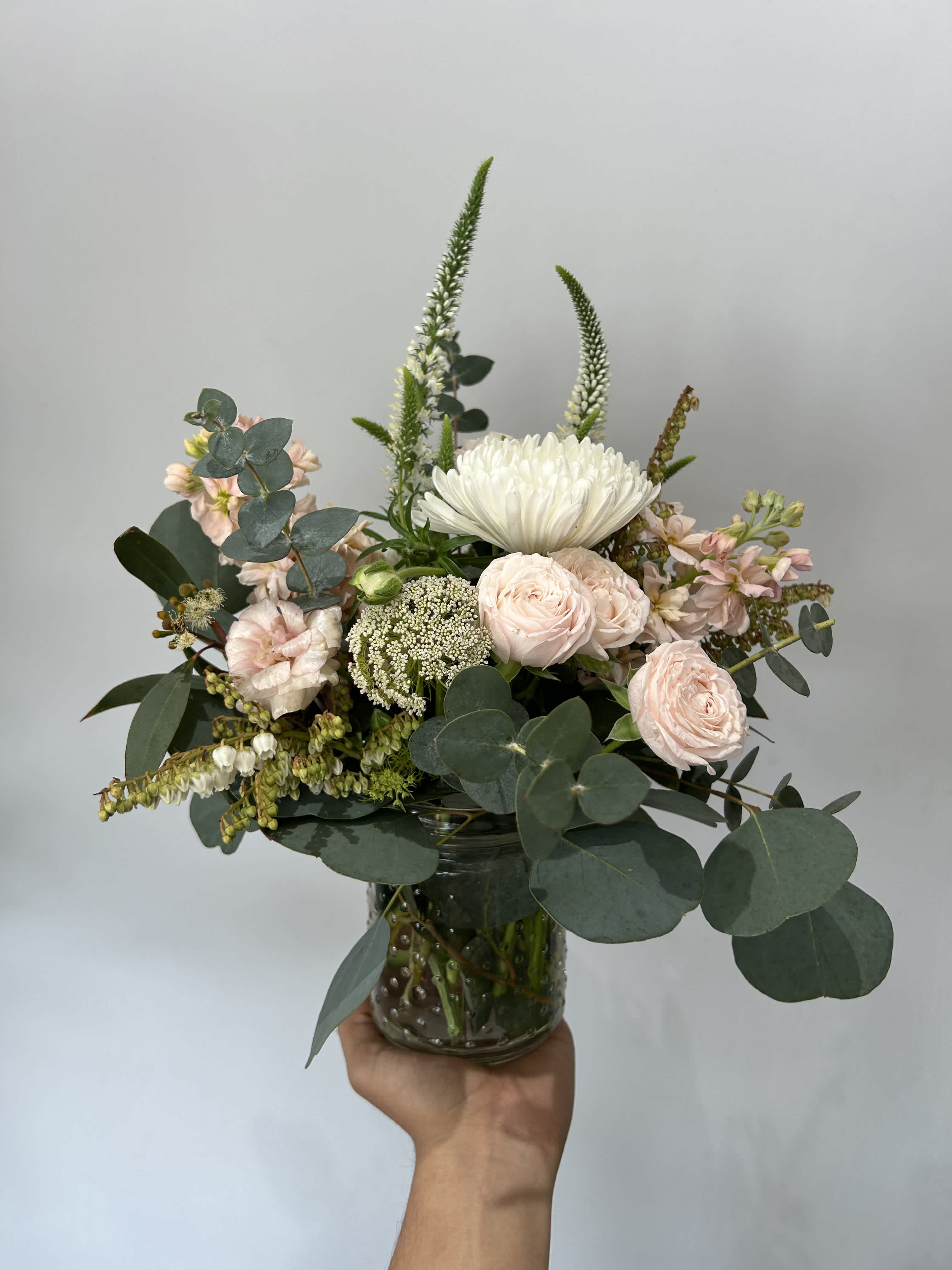 Delicate Blooms  - Seasonal light pink and white flowers arranged with greenery in a vase. 