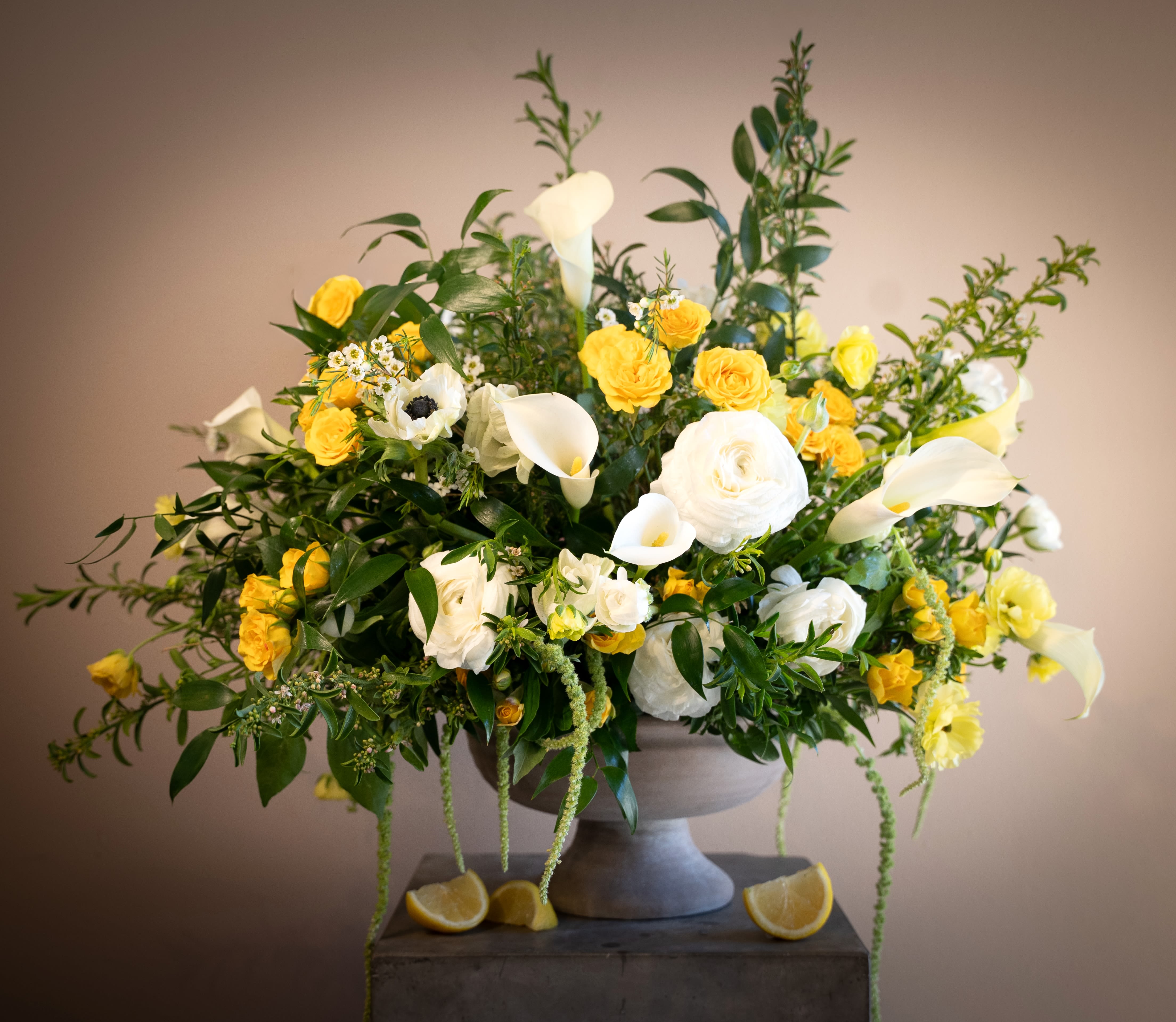  Sole di Capri - Bright and radiant, Sole di Capri captures the golden warmth of the Italian coast. Butter-yellow garden roses mingle with luminous white ranunculus, calla lilies, and delicate anemones, all layered among fresh Mediterranean greenery. Cascading accents and hints of citrus evoke sun-drenched terraces overlooking the sea, creating a design that feels joyful, elegant, and effortlessly luxurious.