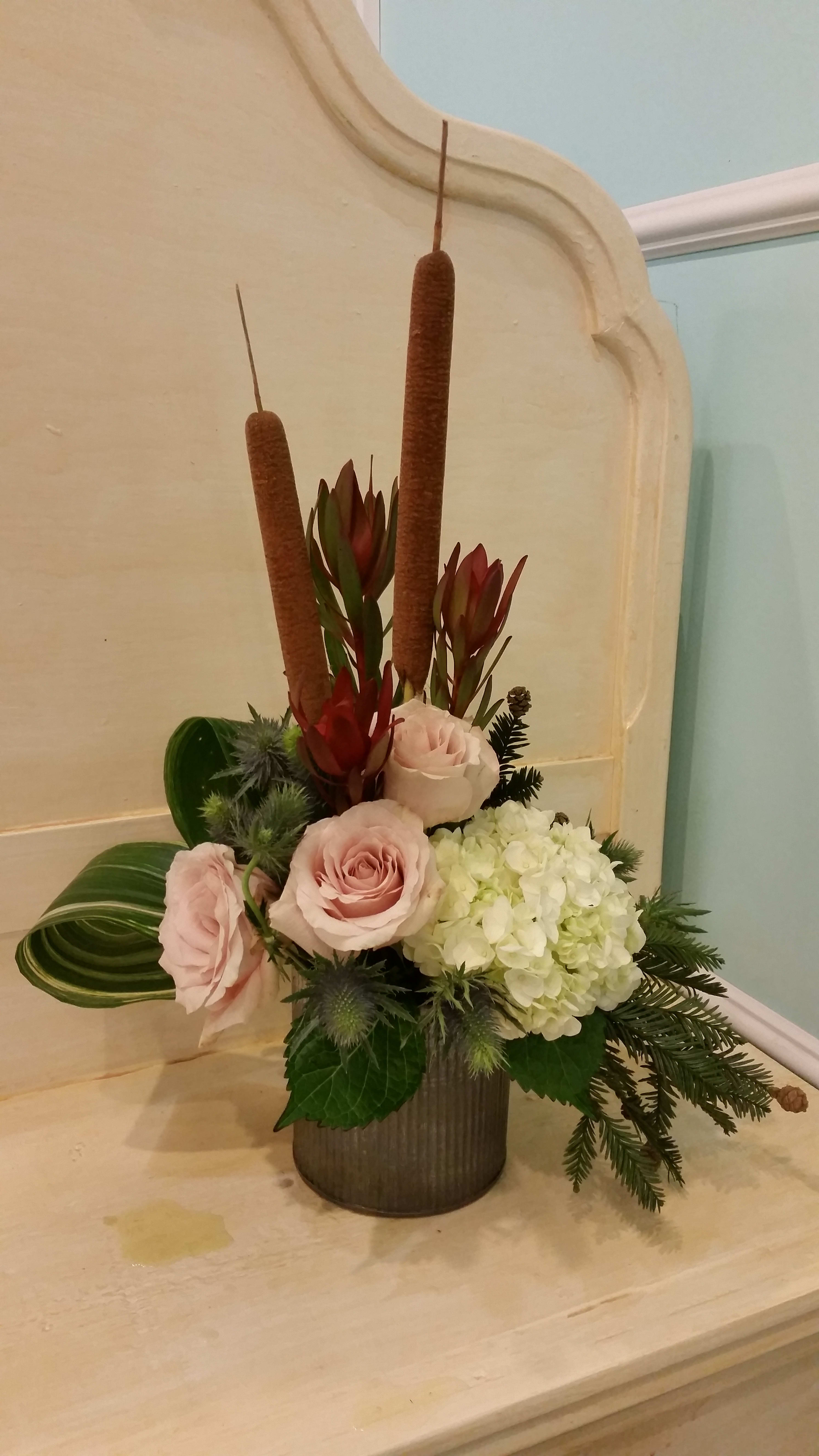Pink roses and white hydrangea in a vase with tall brown cattails