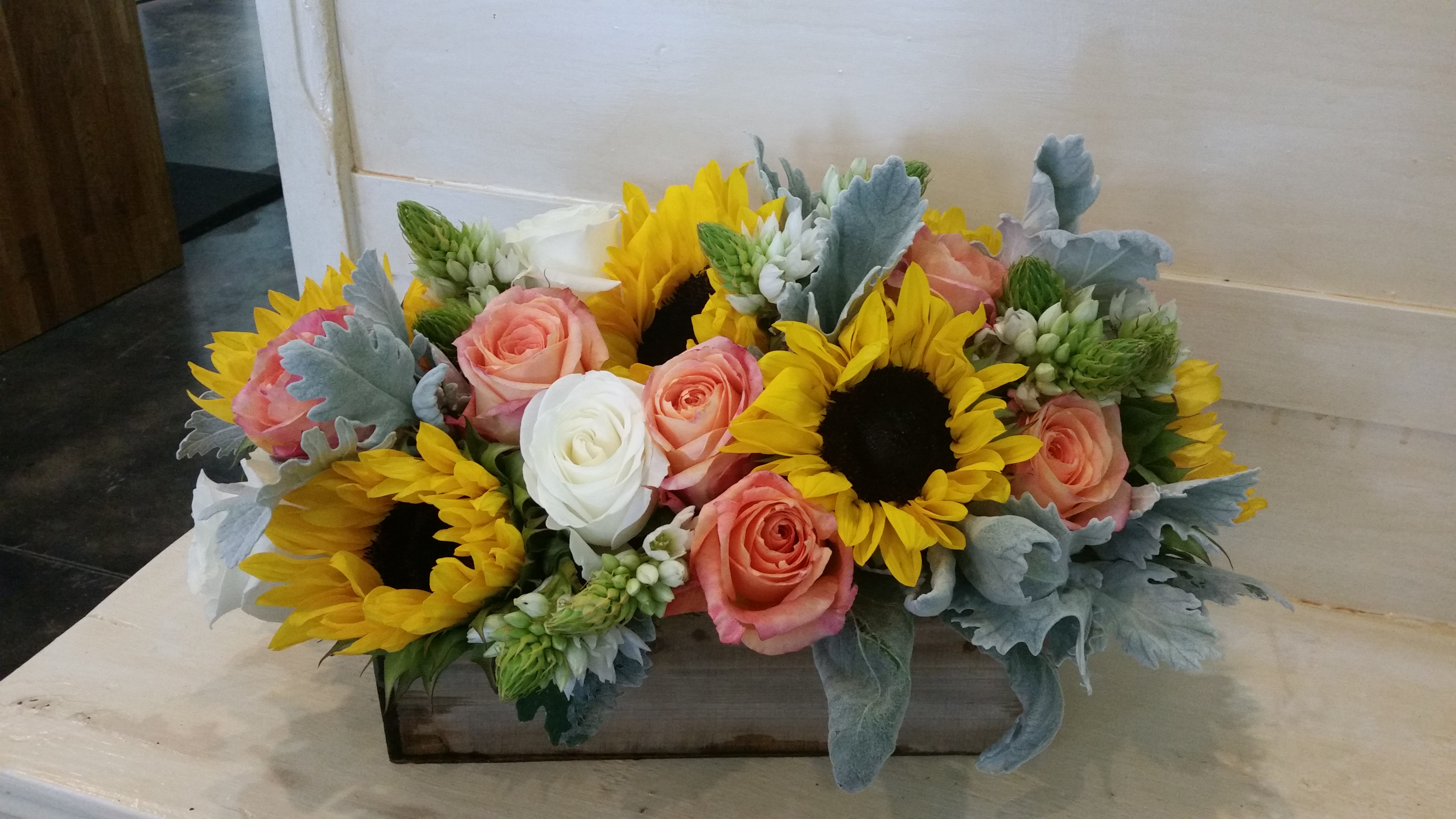 Sunflowers and peach roses arranged in a rectangular wooden box