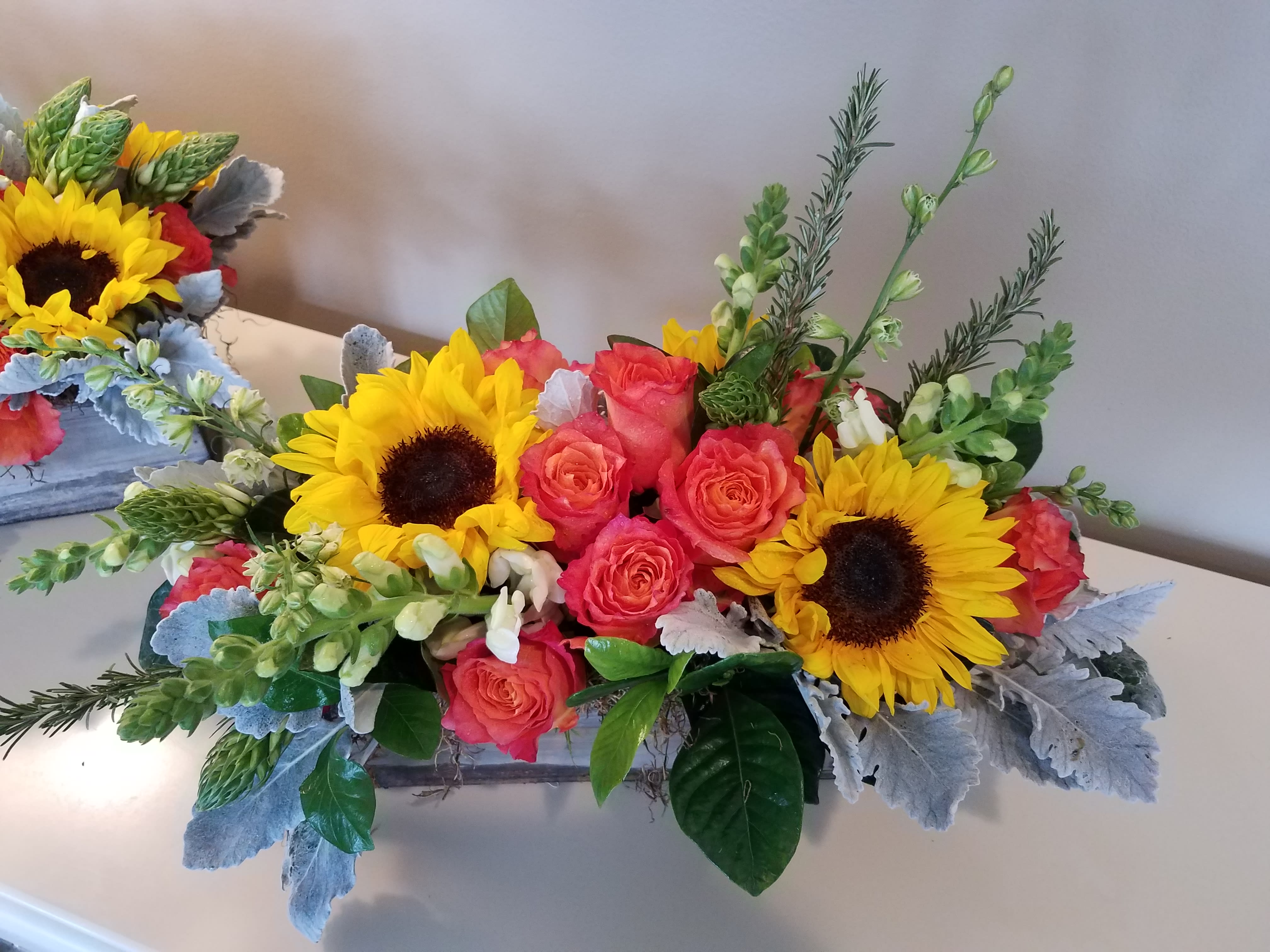 Bright bouquet with sunflowers and coral roses in a low rectangular container