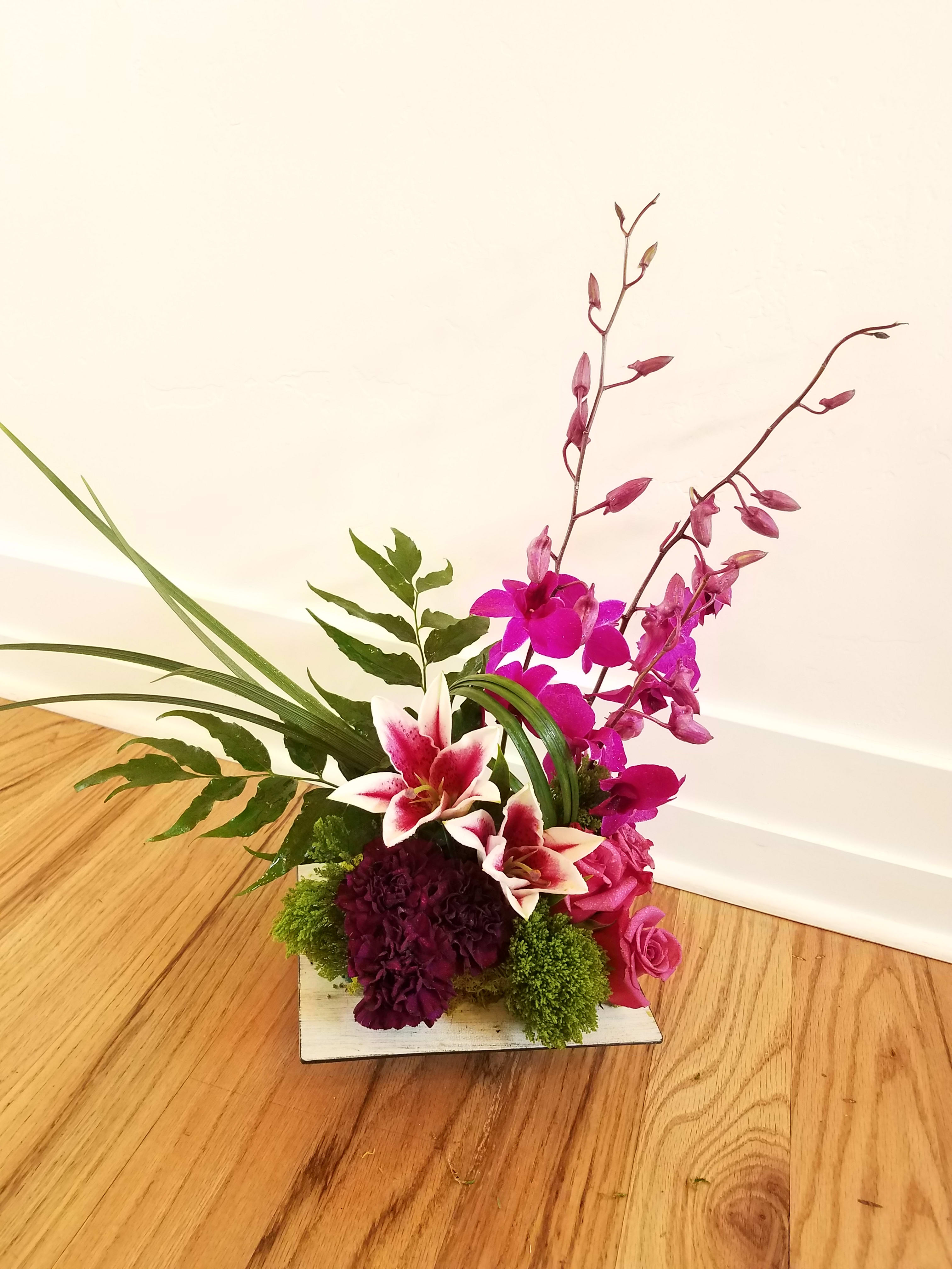 Pink orchid and lily arrangement in a low square container