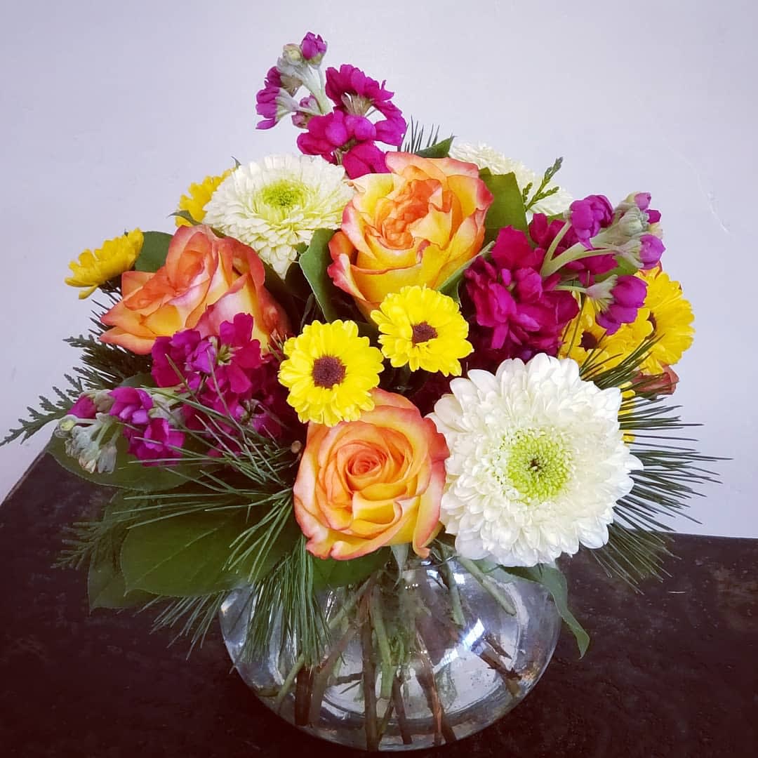 Mixed bouquet of roses and daisies in a clear glass vase
