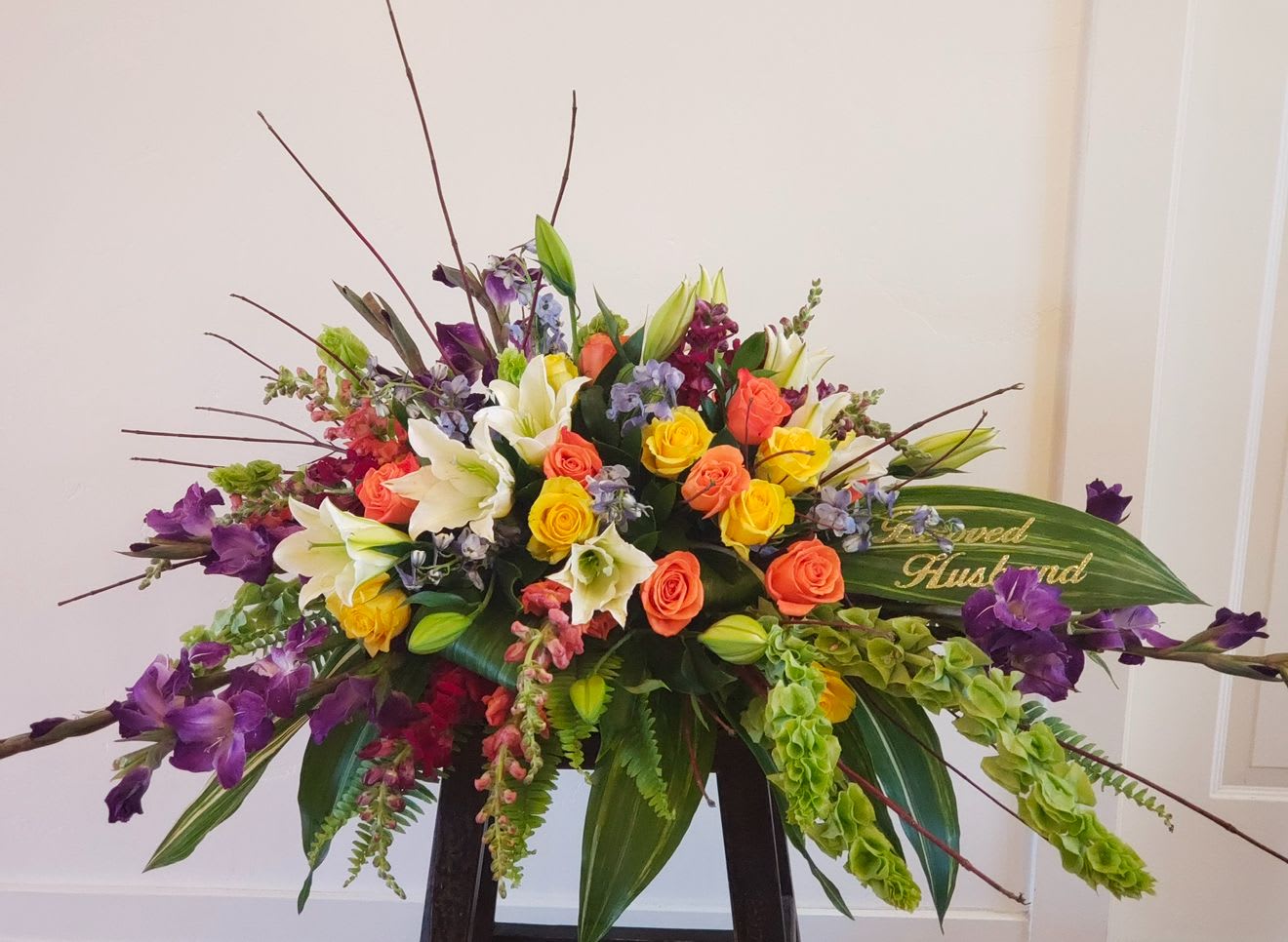 Large mixed bouquet with roses, lilies, and purple flowers in a low container