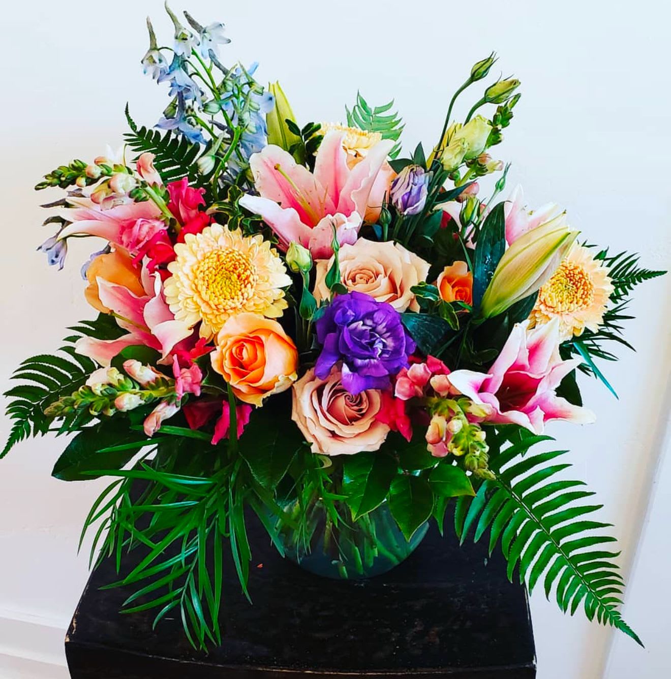 Colorful mixed bouquet in a round vase with lilies and roses