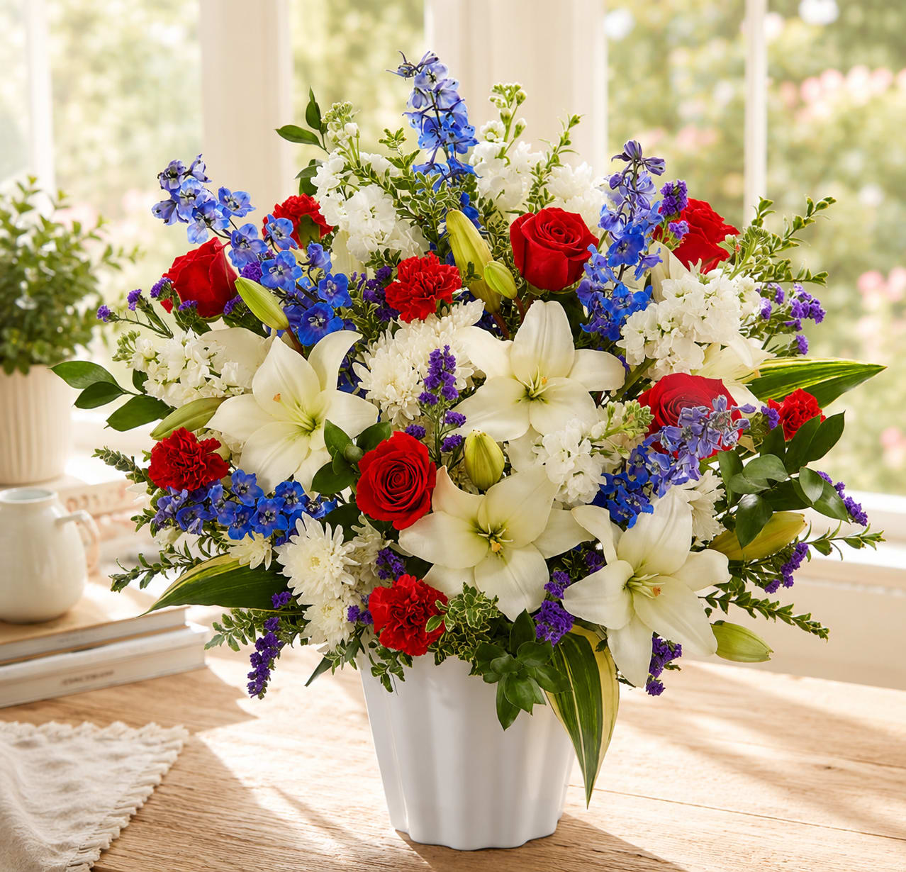 Mixed bouquet of red roses, white lilies, and blue flowers in a white vase