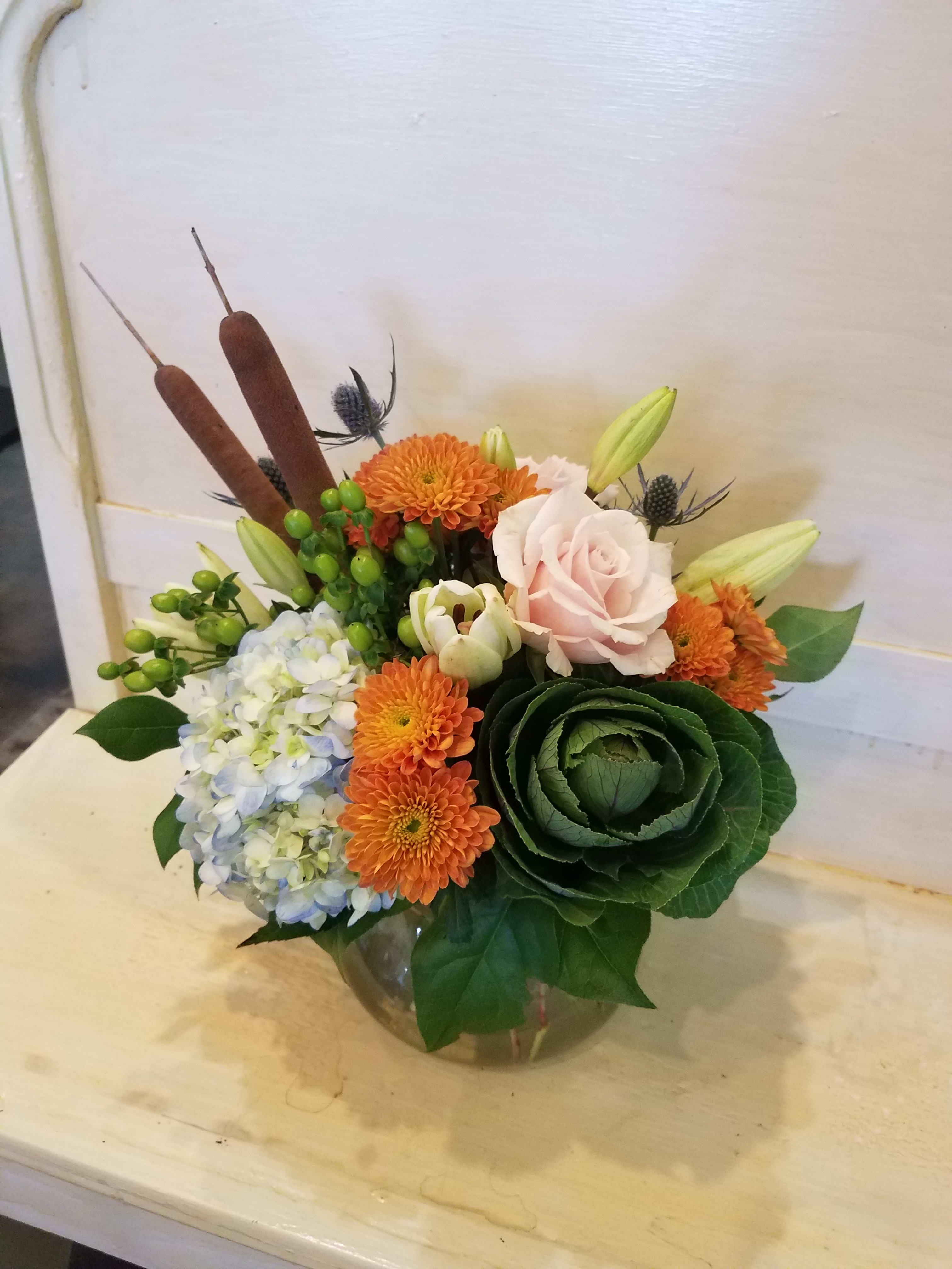 Mixed bouquet in a glass vase with orange and pale pink blooms