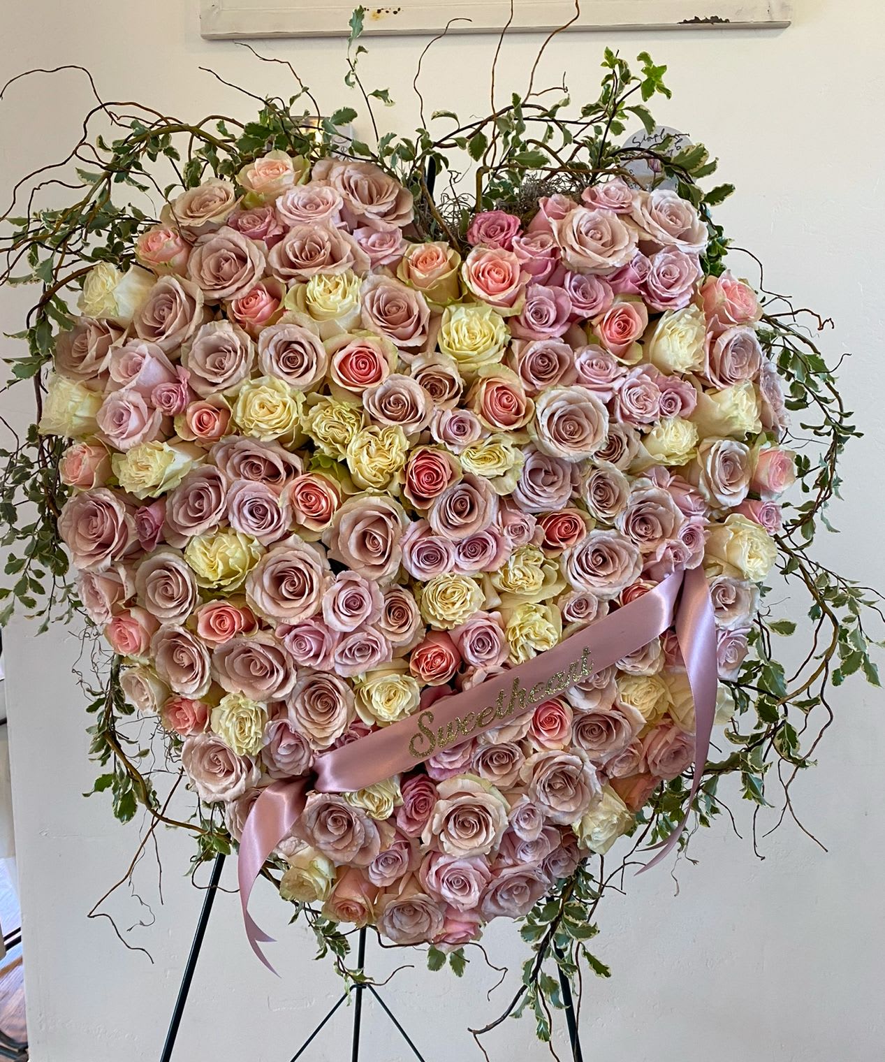 Eternal Love Heart Easel Spray by Simply Flowers - A stunning 24" heart tribute.  Filled with gorgeous, fresh roses in hues of lavender, pinks and whites. Finished off with english ivy and curly willow