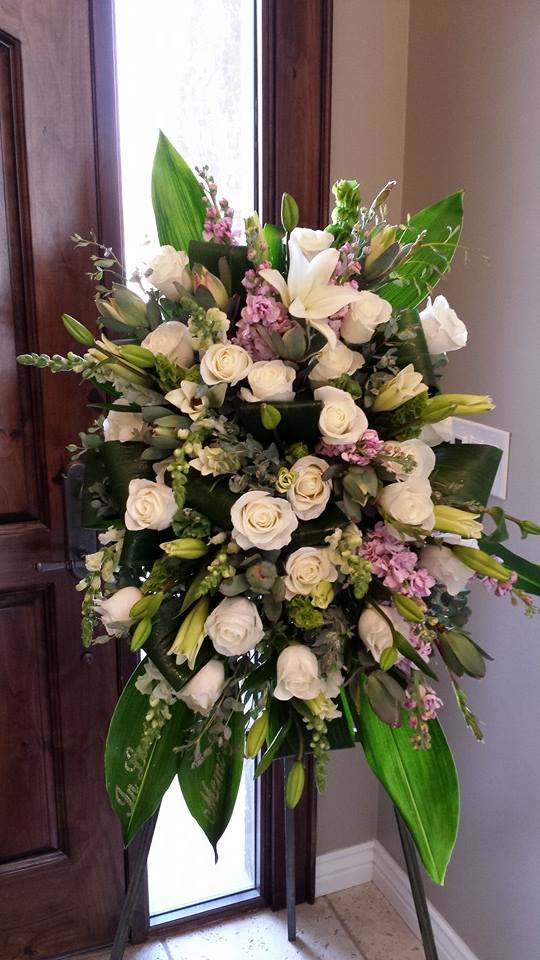Heavenly Embrace Easel Spray by Simply Flowers - A perfectly pure white easel tribute with just a touch of lavender make up this beautiful design. A beautiful, peaceful tribute for a loved one. 
