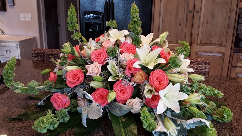 Timeless Blessings Casket Spray by Simply Flowers - A gorgeous design filled with roses in hues of coral and blush. White lilies, bells of Ireland and dusty miller. 