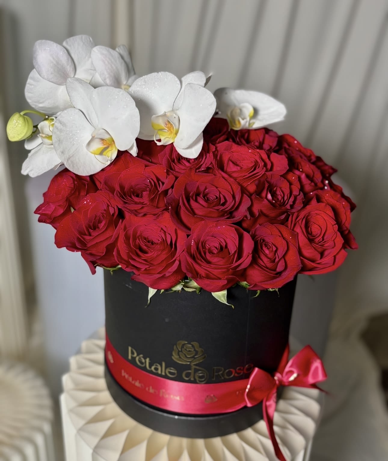 Red roses in a black round box with white orchids on top