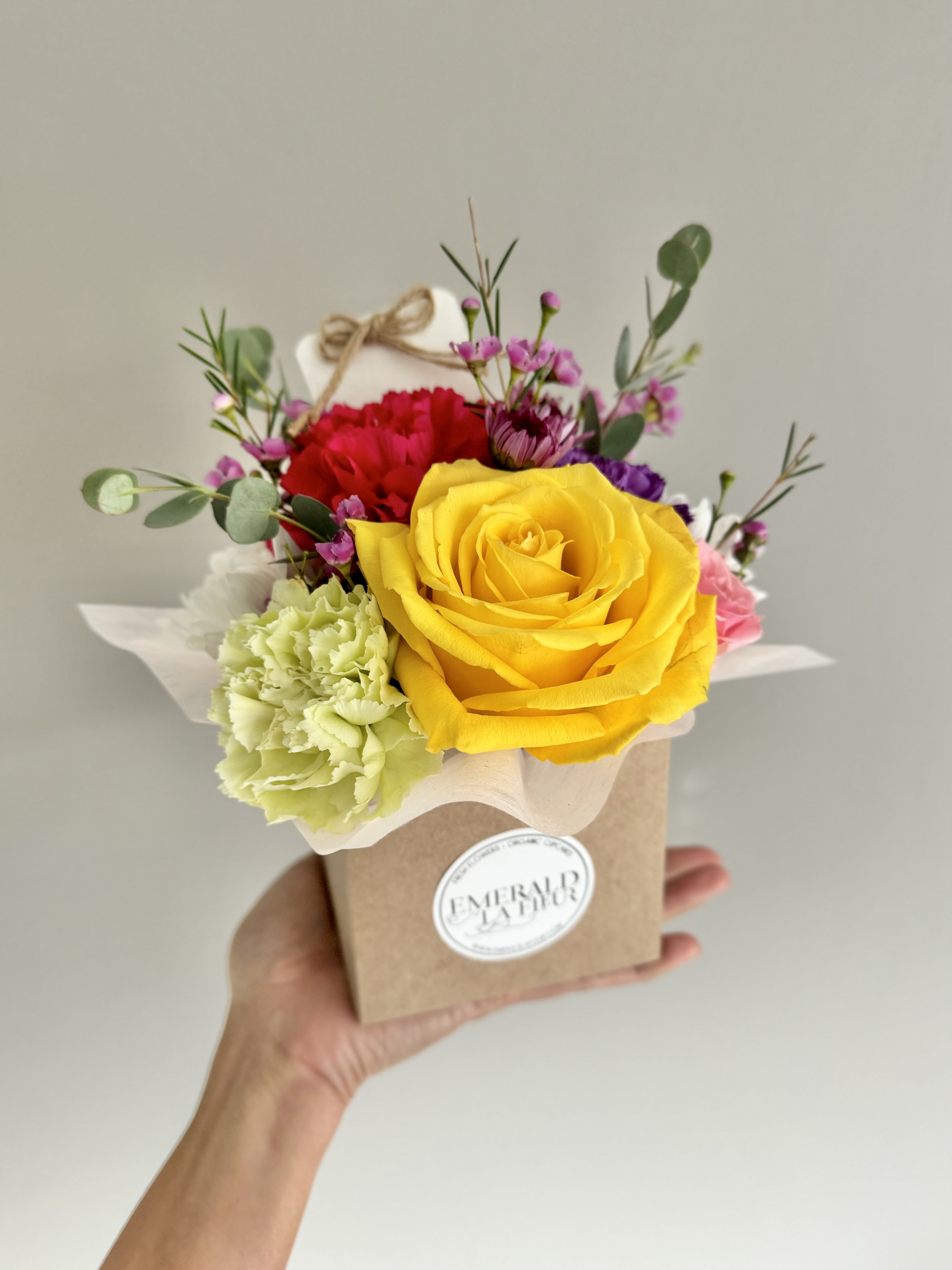 Small mixed bouquet in a kraft box with a yellow rose and red carnation
