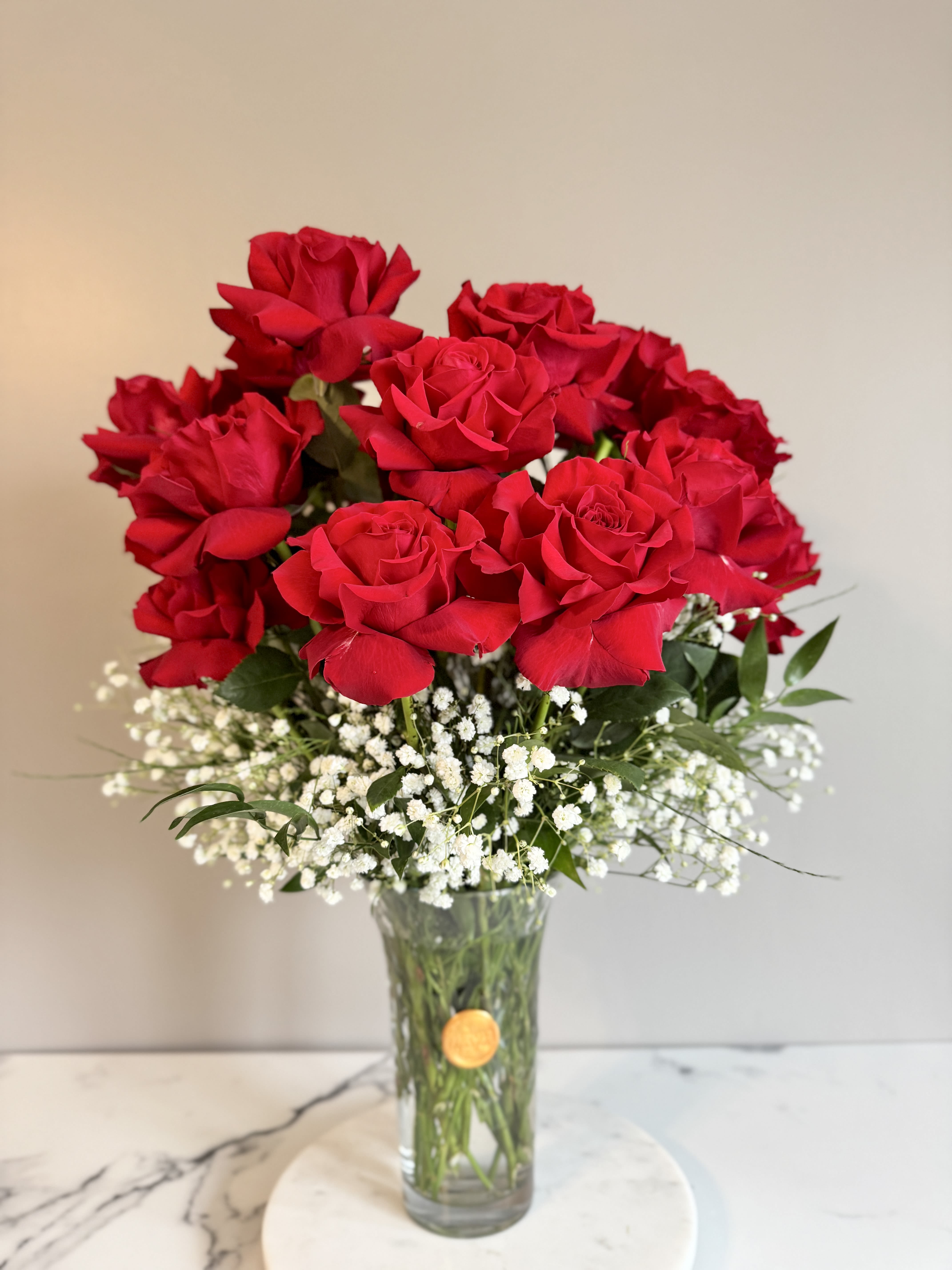 Red roses in a clear glass vase with white baby's breath