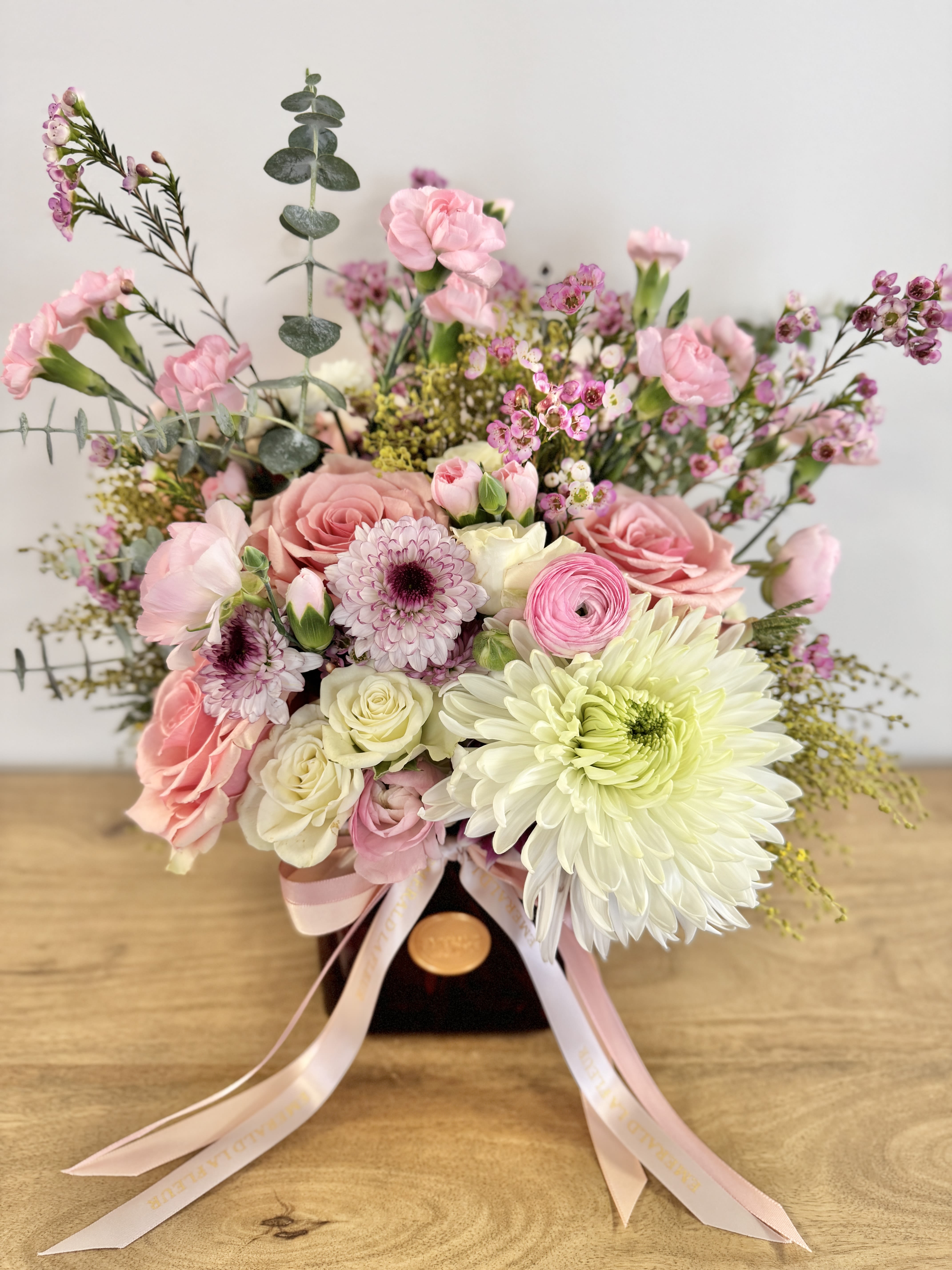 Pink and white bouquet with roses, chrysanthemums, and small filler flowers in a dark vase