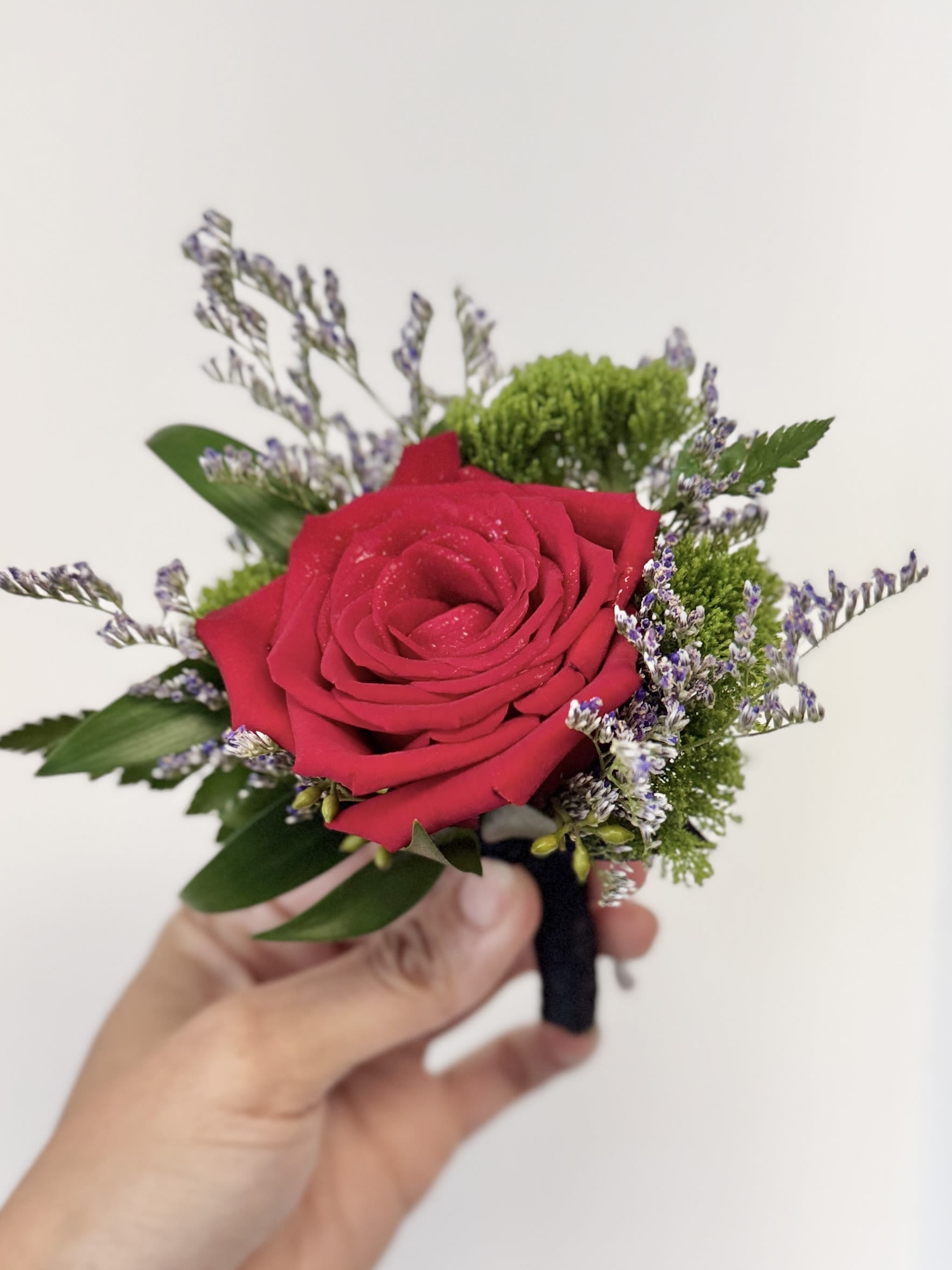 Lapel Boutonniere - A youthful and elegant design especially created by the Florist. Flowers are hand selected by the Florist. Perfect for weddings, prom, homecoming, and school dance.  Please specify preferred color theme in the Florist Instructions when ordering. Colors can be in White, Pink, Blue, Lavender, Orange, Red, Yellow, Green or No Preference.  Boutonnieres are wrapped in ivory ribbon (as pictured).  We highly advise ordering at least 2 days in advance to ensure availability of supplies for the Color Selection.  If your event falls on a weekend, choose Friday delivery. Boutonniere will stay fresh for a few days if kept in a fridge. Delivered in a waterproof box with clear plastic lid.