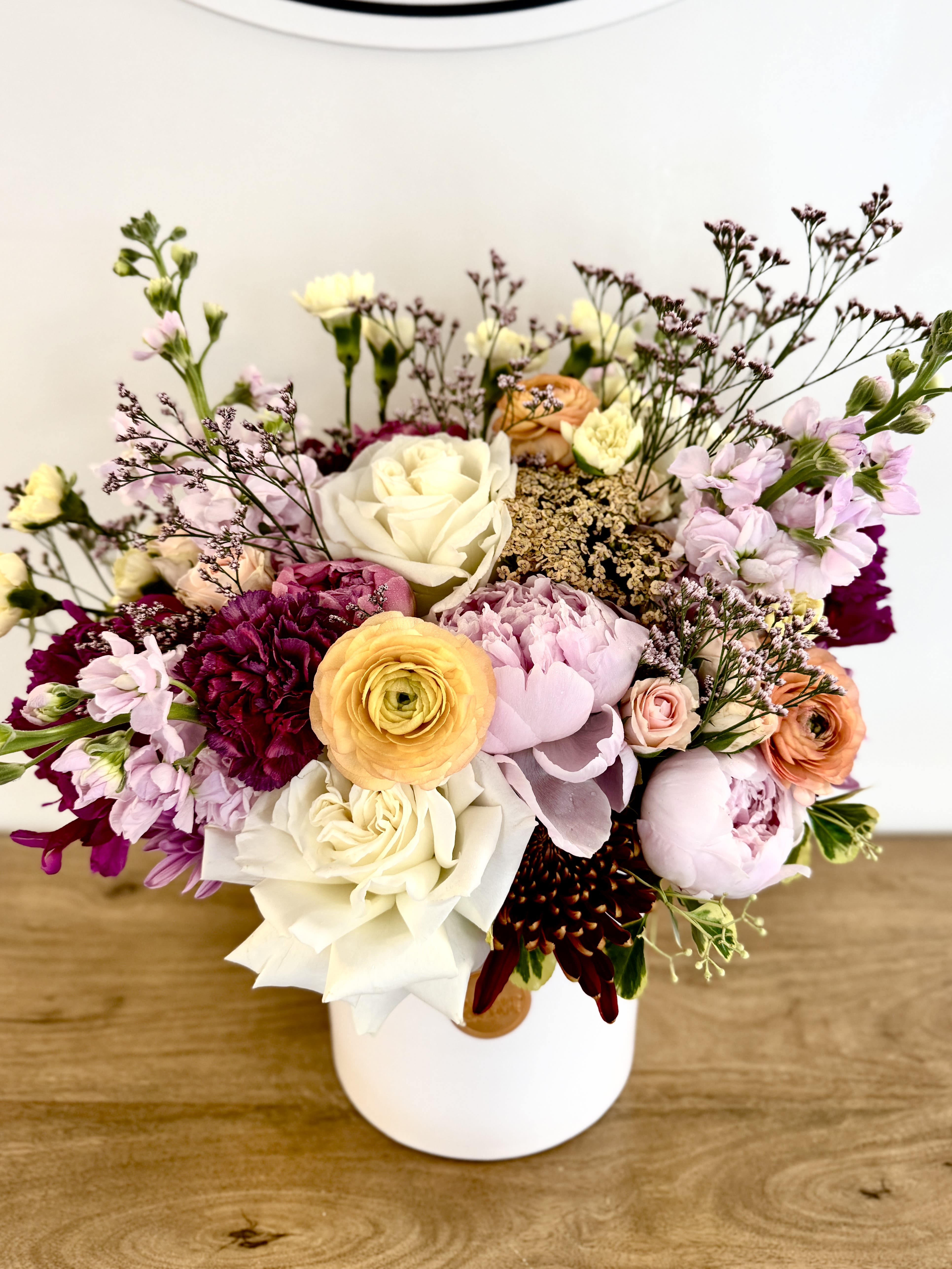 Flora Luxe - A radiant burst of color and texture, Flora Luxe is a lush celebration of spring’s most captivating blooms. Featuring a vibrant mix of roses and a medley of colorful flowers, this garden-style arrangement overflows with elegance and personality. Nestled in a white ceramic vessel, this large floral piece is perfect for birthdays, celebrations, or simply bringing abundance of joy to any space.