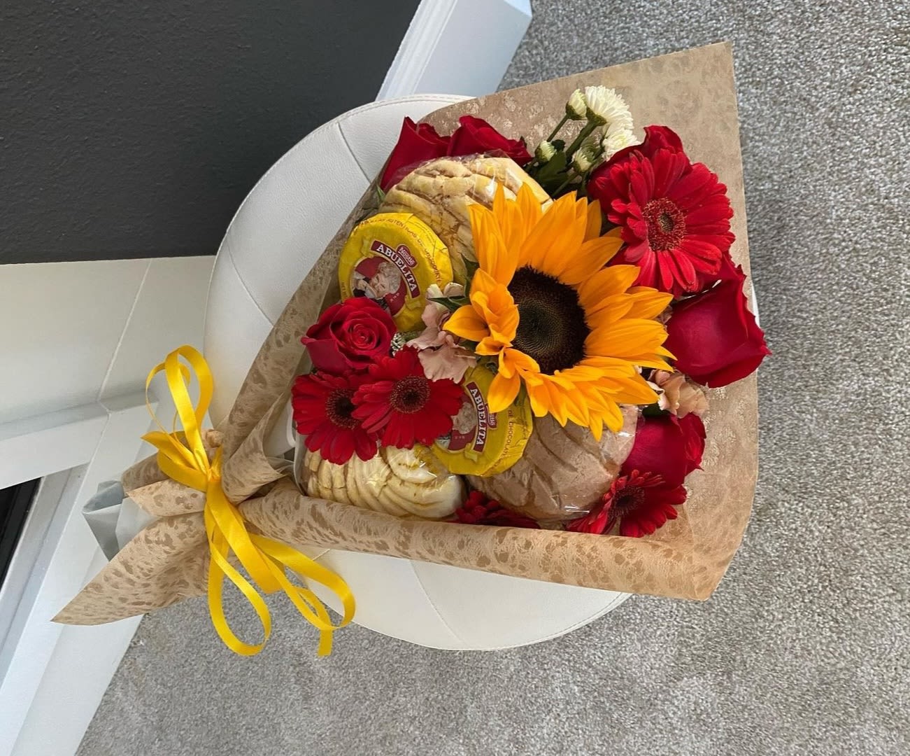 Bouquet of red roses and sunflowers with packaged bread and a yellow ribbon