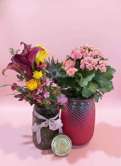 Butterfly jar Bundle  - Bright, cheerful color and a mix of elegant shapes make this Butterfly jar Bundle a joyful choice for a thank-you, thinking-of-you, or housewarming gift. The pairing of a taller arrangement featuring deep purple and sunny yellow calla lilies with a fuller pink cluster of small blooms creates an immediate visual lift-perfect for birthdays, get-well wishes, or simply sending love and romance. The composition reads both celebratory and intimate, the kind of floral surprise that will make the person you're thinking of feel genuinely seen.  The set includes two complementary arrangements plus a small mixed bouquet in a dark glass jar tied with a dotted ribbon, giving the whole bundle a handcrafted, giftable vibe. Expect roses and carnations alongside calla lilies and other seasonal filler flowers in a palette of yellow, white, purple, pink, and red, balanced by broad green foliage. Each piece is presented in its own vessel-glass jar, ceramic vase, and a metal tin accent-so pieces can be displayed together or placed around a home for a coordinated look.  Ideal for Mother's Day, gift sets, or those just-because moments, this bundle suits recipients who love bright color and varied textures. Care is simple: trim stems, refresh water every few days, and keep arrangements out of direct heat to extend bloom life. The mixed sizes make it easy to style on a table, bedside, or kitchen counter, so your gift keeps giving as it brightens their everyday.