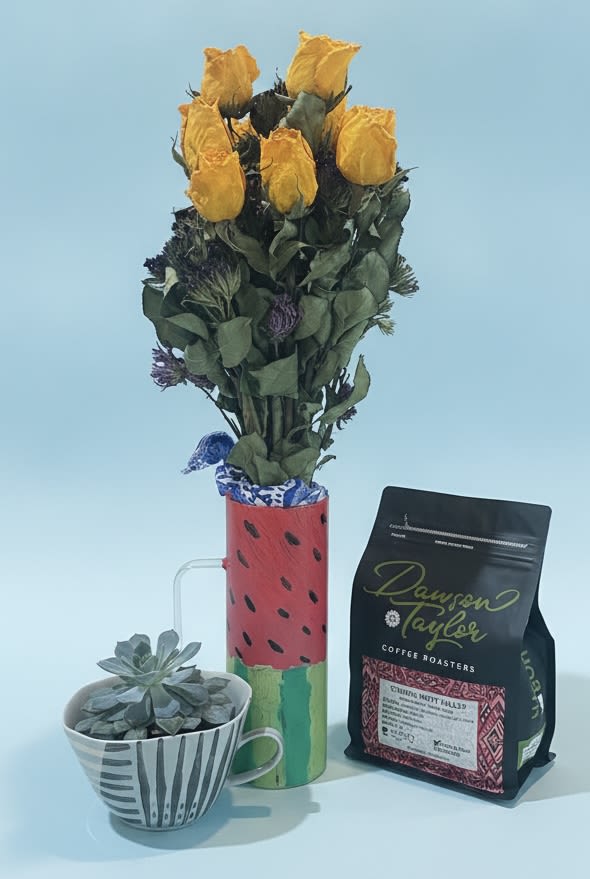 Coffee and succulents mug bundle - Bright yellow roses clustered upright in a painted watermelon-style ceramic mug make an instant sunny statement - perfect as a birthday bouquet, a cheerful housewarming gift, or a Father's Day pick-me-up that feels both playful and thoughtful. The arrangement reads fresh and casual, sending a message that the person you're thinking of is seen and celebrated; add the included coffee bag to make it a warm "just because," thank-you, or get-well gesture they can enjoy with a quiet moment.  A low, compact succulent in a striped ceramic bowl balances the tall rose display for a pleasing mix of height and texture. Colors lean into green, yellow, red, and black accents across the mug, bowl, and decorative ribbon; the set includes a ceramic mug, ceramic bowl, succulent, a small cluster of roses, a bag of coffee, and coordinating ribbon. The roses sit neatly above the mug for an upright profile while the succulent offers a long-lasting, low-care companion piece.  This bundle suits spring and summer occasions as well as year-round celebrations - from thinking-of-you and retirement to anniversaries, weddings, Valentine's Day, Mother's Day, or an "I'm sorry" peace offering. Care is simple: keep stems in fresh water and place the succulent in bright, indirect light; the included coffee completes the gift set for an immediately delightful unboxing.