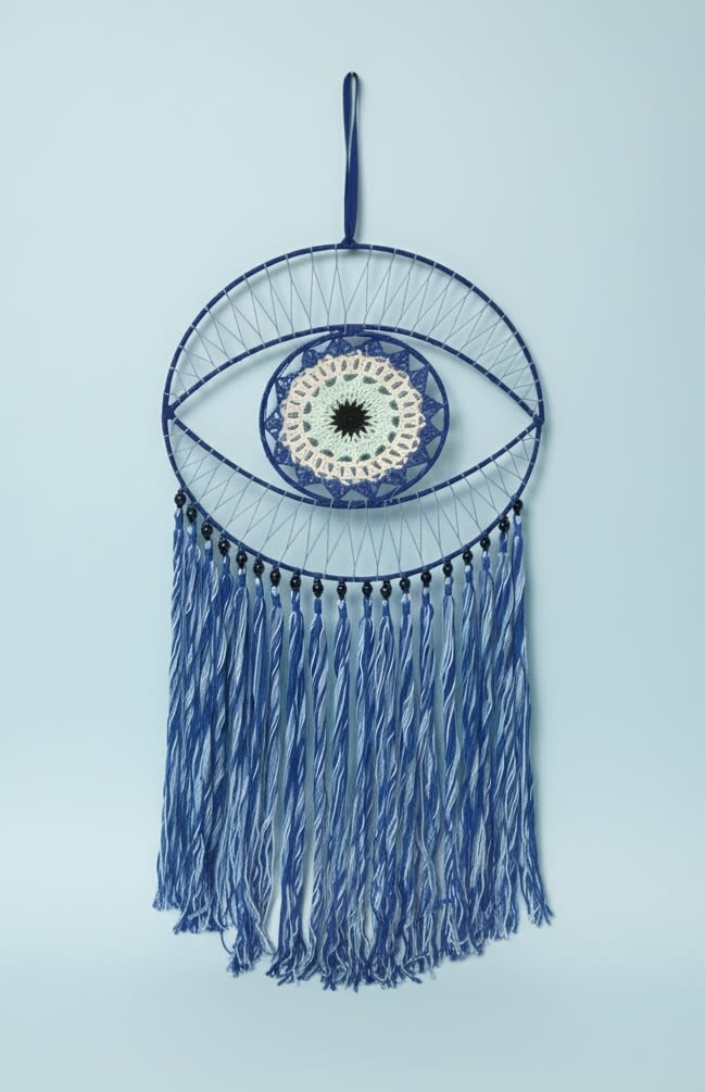 Evil Eye Dream catching Bundle - Bright, artful, and slightly bohemian-this flower arrangement and wall-hanging bundle makes a housewarming or birthday gift feel personal and thoughtful. The set pairs a woven evil-eye wall hanging-deep blue cord, a circular woven center and long blue-and-white tassels-with a sculptural floral accent: a single yellow spider chrysanthemum arranged in a rounded cobalt-blue glass vase. It's the kind of present that says "I'm thinking of you" or "just because" while doubling as decor the recipient will keep on display.  The chrysanthemum's long curling petals and airy filler stems create a minimalist, contemporary silhouette against the rich blue glass; nearby clear and red glass vases in the image suggest the bundle's lively color story of orange, blue, yellow, red, white and textured neutrals. The woven hoop's layered texture and hanging tassels add hand-crafted charm-perfect for best friends, New Year gifting, or someone settling into a new home. Simple care: keep the single stem in fresh water and hang the woven piece out of direct sun to preserve color and texture.