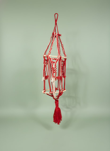 Large Macrame Plant hanger - Handmade red-and-white macrame brings a warm, tactile pop to holiday décor or everyday rooms-perfect as a Christmas accent, a housewarming gift, or a thoughtful "just because" surprise. This large macrame plant hanger reads as a decorative hanging ornament with a festive, folk-art feel that also suits Father's Day, birthdays, and spring refreshes; the person you're thinking of will notice the bright red highlights against the pale cord and the artisan, handcrafted vibe.  The elongated, symmetrical form is woven from red and white cord with beaded ring sections and a full tassel at the bottom, creating an open, lightweight structure that layers beautifully over textured walls, porches, or window nooks. While designed as a hanging ornament rather than a floral arrangement, it pairs easily with potted plants or can hang solo as a seasonal accent-its clean lines and bold color contrast make it equally at home in modern and rustic settings.  Give it to someone moving into a new home, tuck it into a gift set for Mother's Day or Earth Day, or let it be a small-but-memorable token for Thinking of You moments; it arrives ready to hang and requires no care, so the recipient can enjoy the instant visual lift right away.