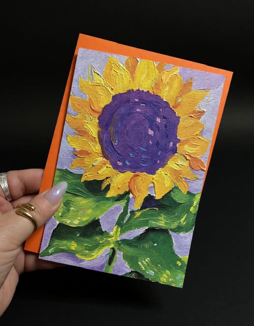 Painted Sunflower blank card-all occasion - A bold, hand-painted sunflower greets the recipient on this all-occasion greeting card-perfect for a birthday bouquet, a cheerful "thinking of you," or a warm Father's Day note. The large sunflower with bright yellow petals and a deep purple center makes an immediate visual impact, so the person you're sending it to will feel seen and celebrated the moment they open it.  The artwork is textured with thick brushstrokes and a vivid orange border that frames the composition, while green leaves fill the lower half against a soft lavender background for lively contrast. The card comes blank inside, letting you tailor the message for graduations, new babies, anniversaries, retirements, thank‑yous, get-well wishes, summer greetings, or just-because moments.  Lightweight and easy to tuck into a bouquet or mail on its own, this painted sunflower card pairs beautifully with fresh sunflowers or mixed arrangements to complete a thoughtful gift. Simple care: keep flat and dry - the painted surface and colors are vivid and designed to brighten someone's day season after season.