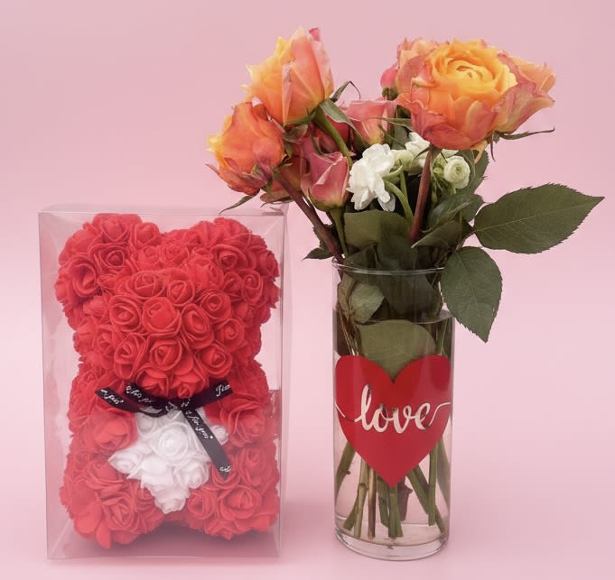 Rosy Bear with bouquet of fresh roses (each one is custom made so variation is pictured) - A playful, affection-filled gift that feels like a hug: a small bouquet of fresh roses paired with a red rose teddy bear makes a perfect anniversary or love-and-romance surprise. This flower arrangement also works beautifully for birthdays, "just because" moments, or to say thank you or thinking of you-its cheerful mix and charming presentation will make the recipient feel genuinely seen and adored, whether you're celebrating a wedding milestone or Father's Day with a romantic twist.  The bouquet sits in a clear glass vase and combines warm orange and soft pink roses with a few crisp white accent blooms for contrast, tied with a ribbon and finished with a heart-shaped love tag. The companion teddy bear is crafted from tightly packed red rose heads with a white flower accent and a black ribbon, presented inside a clear plastic gift box for an unboxed-wow moment. Compact and ribboned for gifting, this set arrives ready to place on a bedside table, desk, or mantle-an immediate lift for the person you're honoring.
