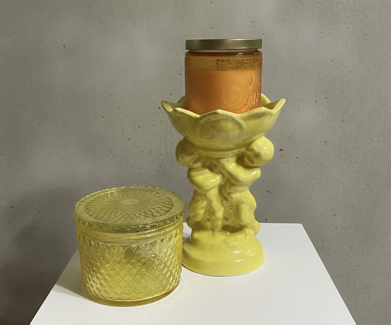 Sunflower Cherub candle set - A warm, modern gift that lights up any room: this sunflower-themed candle set pairs sunlit yellow and glowing amber tones to give the recipient a cozy, celebratory feeling. Perfect as a housewarming, birthday, thank-you, or "just because" present, the arrangement reads like a seasonal holiday accent while remaining fresh for weddings, new baby welcomes, or a thoughtful thinking-of-you gesture.  The set includes a tall yellow ceramic candle holder with a sculpted pedestal silhouette, a short textured yellow glass jar with a lid, and a third orange glass jar nested in the taller holder for a layered amber-and-gold palette. Though the design is decorative rather than a traditional bouquet, the sunflower inspiration comes through in the cheerful yellow and orange color story and glossy, ornamental finishes-ideal for mantels, entry tables, or bedside dressers.  Give someone the kind of gift that feels both personal and polished: it brightens a space and signals care without fuss. Designed for easy display and everyday enjoyment, the pieces arrive ready to style; no special care is needed beyond normal candle safety, making this a simple, elegant choice for occasions from Valentine's Day to a new home celebration.