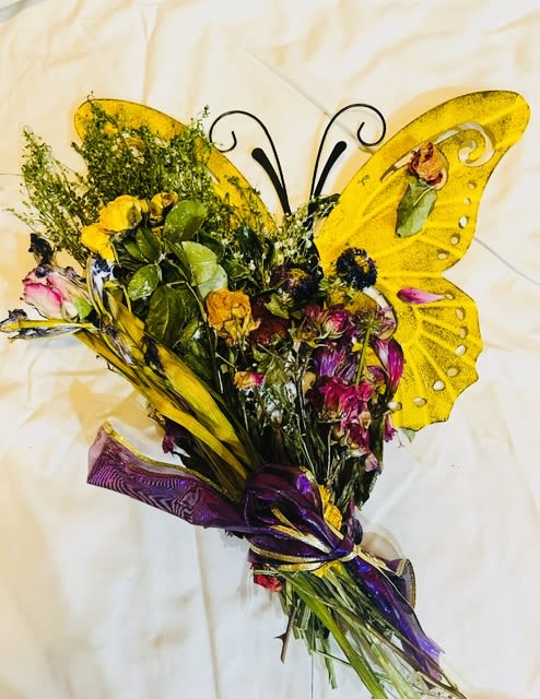 preserved Butterfly flowers - A playful butterfly-shaped flower arrangement that instantly feels like a celebration - perfect as a cheerful birthday bouquet, a congratulatory gift, or an everyday surprise to brighten someone's day. The design mimics butterfly wings with large yellow panels framing a lively cluster of preserved blooms in yellow, purple, pink, green, and white, so the person you're thinking of will feel noticed and delighted the moment they see it.  The preserved mix features roses, carnations, daisies and other mixed blossoms arranged with leafy filler for a textured, handcrafted look. Decorative butterfly wings and a purple ribbon gather the stems in one version; an alternate style centers the flowers on a butterfly wall decoration with cream and yellow roses, smaller pink and peach blooms, and a tied white ribbon. Clear wrap protects the bouquet while keeping the whimsical details visible.  Ideal for spring décor, a cheerful anniversary, or as a keepsake gift that lasts longer than fresh flowers, these preserved arrangements require no watering and retain their color and shape for months when kept out of direct sunlight and away from humidity. Choose the winged bouquet or the wall-mounted design to match the recipient's space and the moment you want to make memorable.