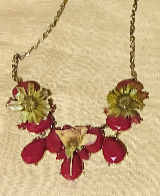 red resin and daisy and flowers necklace - Bright, playful and unexpectedly wearable, this floral necklace is a charming take on a flower arrangement for casual celebrations and everyday gifting. As a fashion-forward accessory for birthdays or "just because" moments, the petite cluster of blossoms across a delicate metal chain sends a cheerful, feminine message-she'll feel noticed and celebrated the moment she puts it on.  The front features bright pink petal-like resin elements accented by sunny yellow and crisp white miniature blooms set in a beaded floral jewelry setting. The compact scale and lightweight chain make it comfortable for all-day wear, with the clustered arrangement sitting like a petite bouquet at the collarbone. The mix of pink, yellow and white offers a sunny, springlike palette that pairs easily with dresses or a simple tee.  Perfect for gifting to a friend, daughter, or bridesmaid who loves whimsical accessories, this piece reads like a wearable corsage-ideal for garden parties, birthdays, or to mark a small milestone. Treat it like jewelry: avoid moisture and store flat when not wearing to keep the beads and metal chain looking fresh.