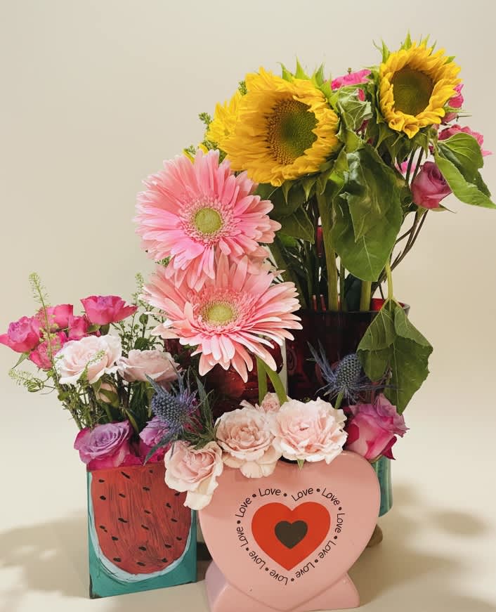 Mixed bouquet with sunflowers, pink gerberas, and roses in decorative containers