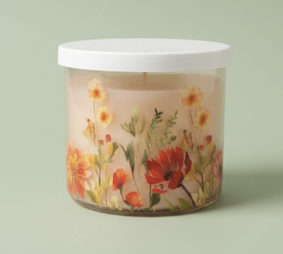 floral room candle - A soft watercolor of daisies and spring blossoms wraps a clear glass jar, giving this floral room candle a gentle, everyday charm perfect for a birthday, thank-you, or just-because gift. The pastel pink, orange, and green palette and clean cylindrical shape make it an understated decorative accent that will make the person you're thinking of feel noticed and comforted without overpowering their space.  The candle comes in a clear glass jar with a flat white lid and pale cream/peach wax, the label showing delicate orange, pink, red, and yellow blooms with light green stems. Lightweight and minimal in profile, it works equally well on a bedside table, bathroom shelf, or kitchen windowsill as a standalone accent or an add-on to a bouquet.  Choose this as a simple home-fragrance gift when you want to say "I'm thinking of you" - it's the kind of present that brightens a room and the recipient's day. Burn on a level, heat-resistant surface; keep wick trimmed and never leave unattended.