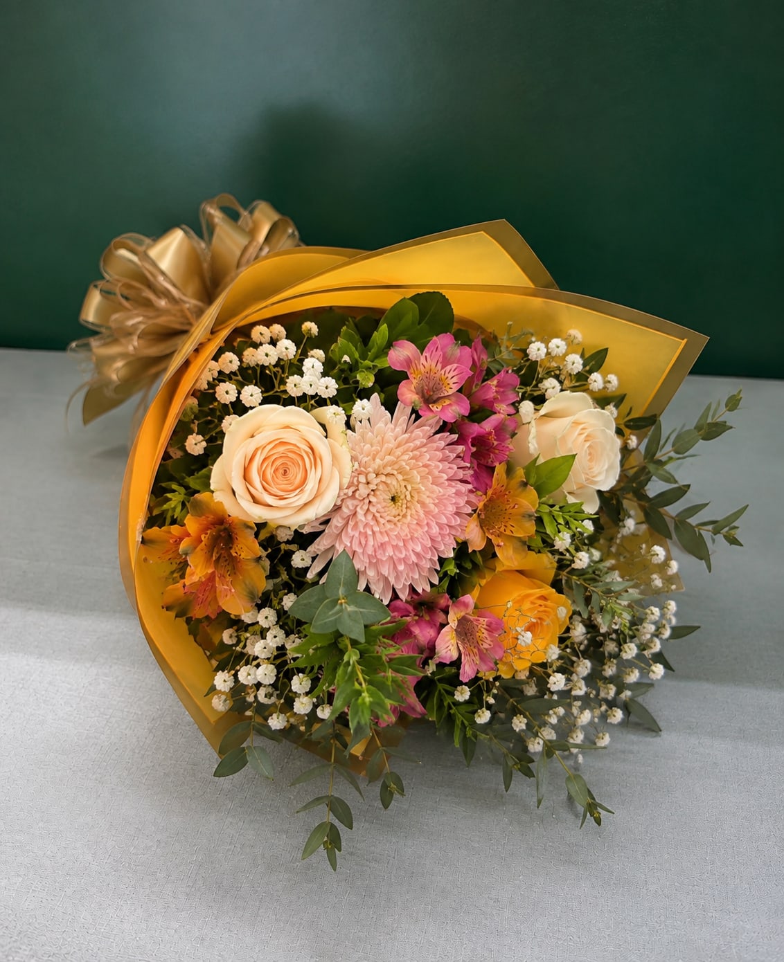 Bouquet of peach and pink flowers wrapped in gold paper