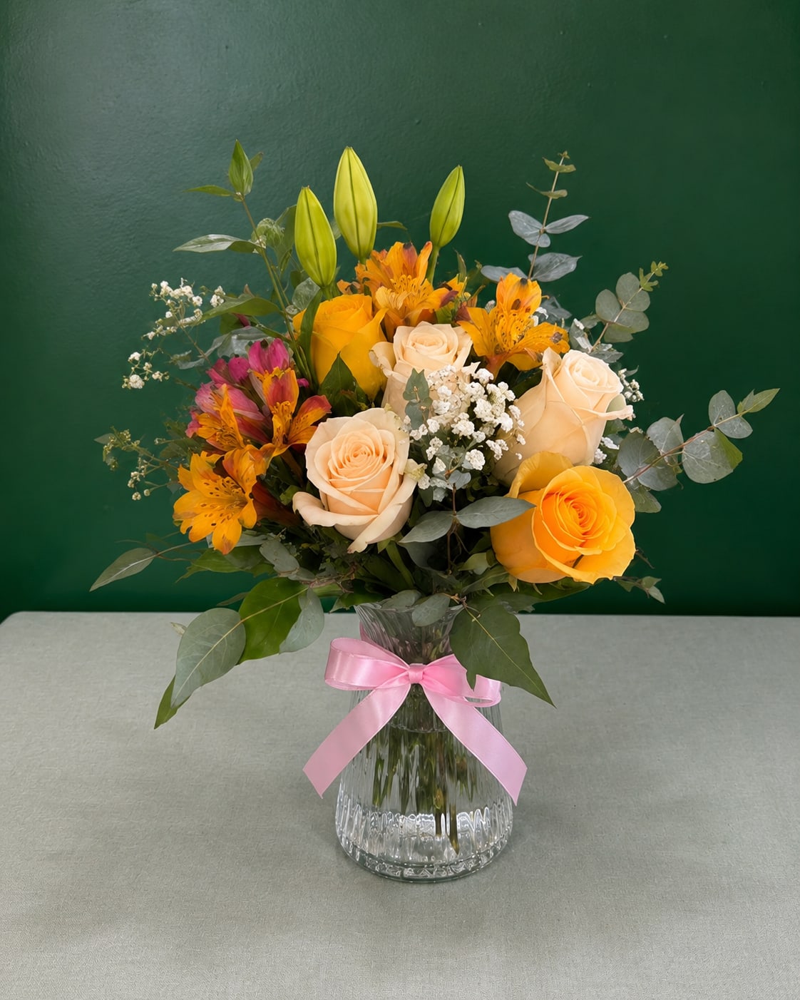 Bouquet of yellow and cream roses with orange flowers in a glass vase
