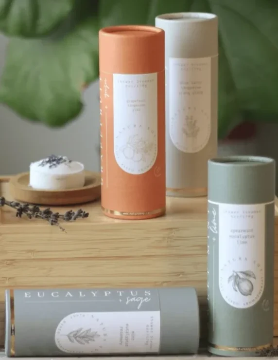 Assorted cylindrical candle tubes on a wooden surface with a small candle dish