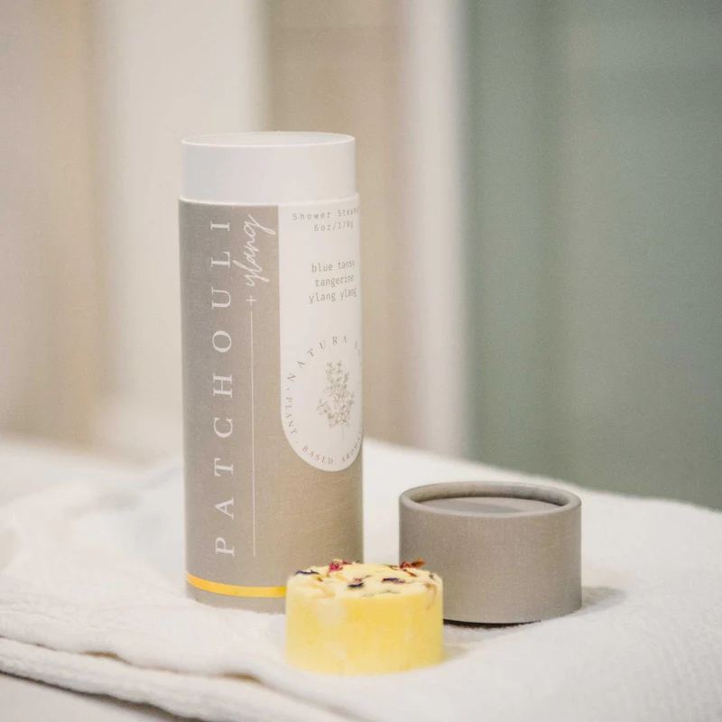 Patchouli shower steamers in a tube with a small yellow bar and lid