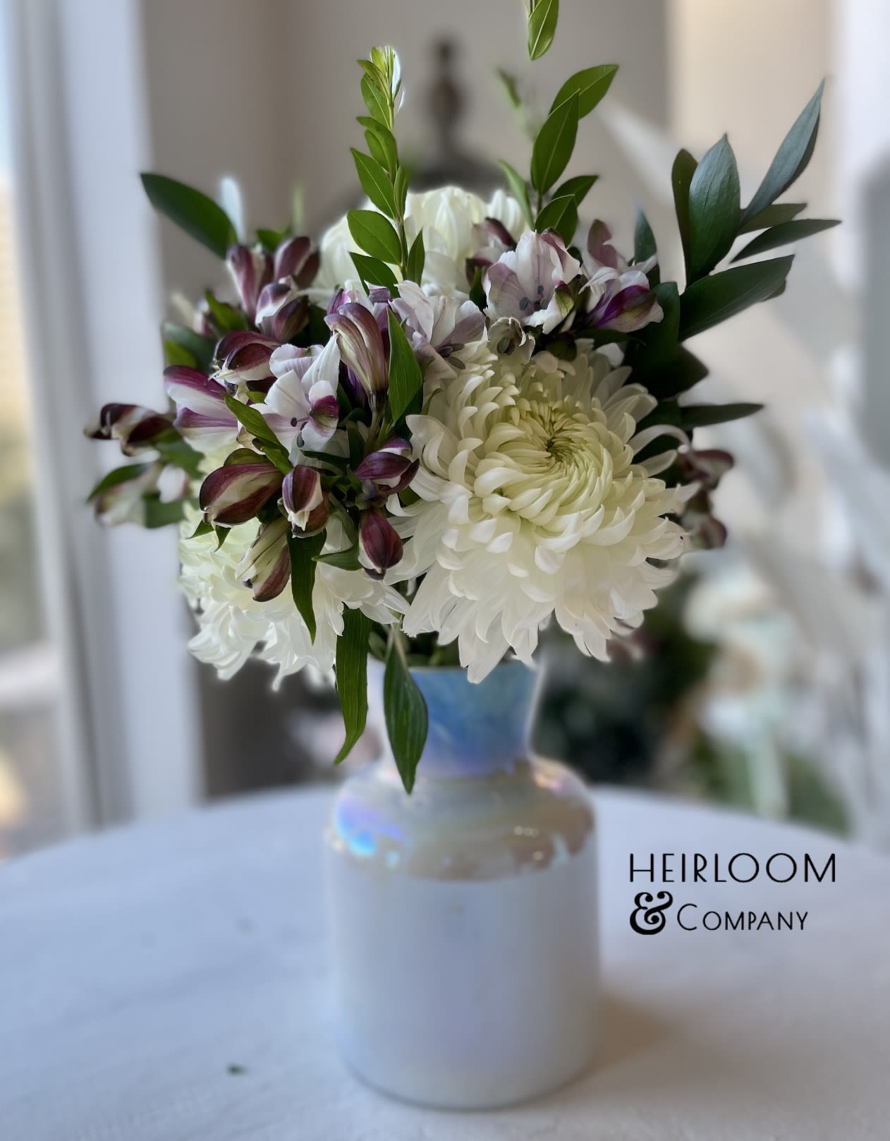 White chrysanthemums and purple alstroemeria in a white vase