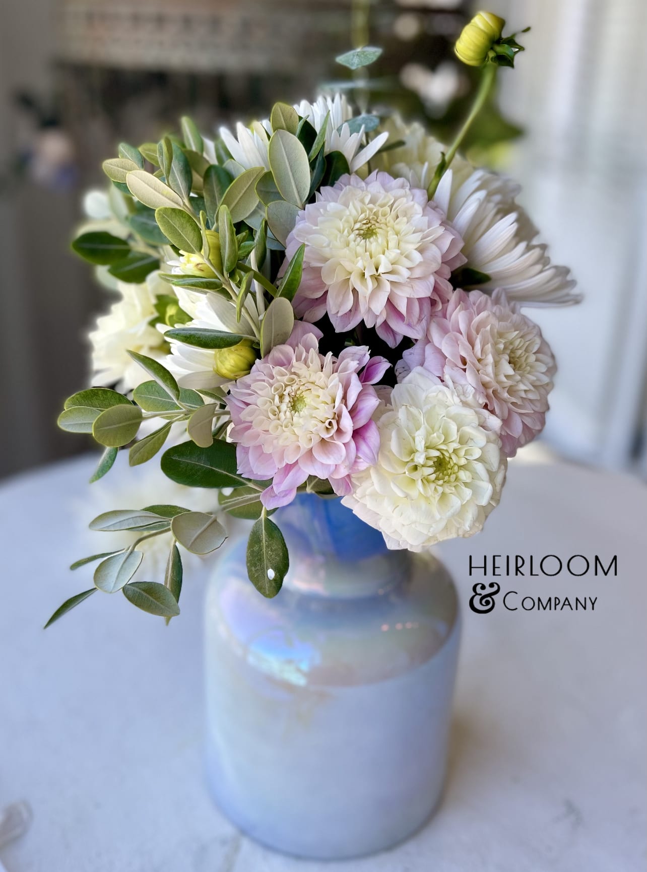 Pink and white flowers arranged in a glass vase with greenery
