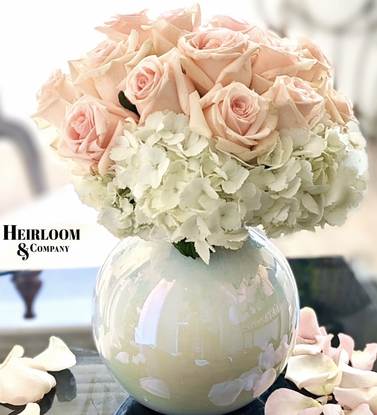 Blush pink roses and white hydrangeas in a round glass vase