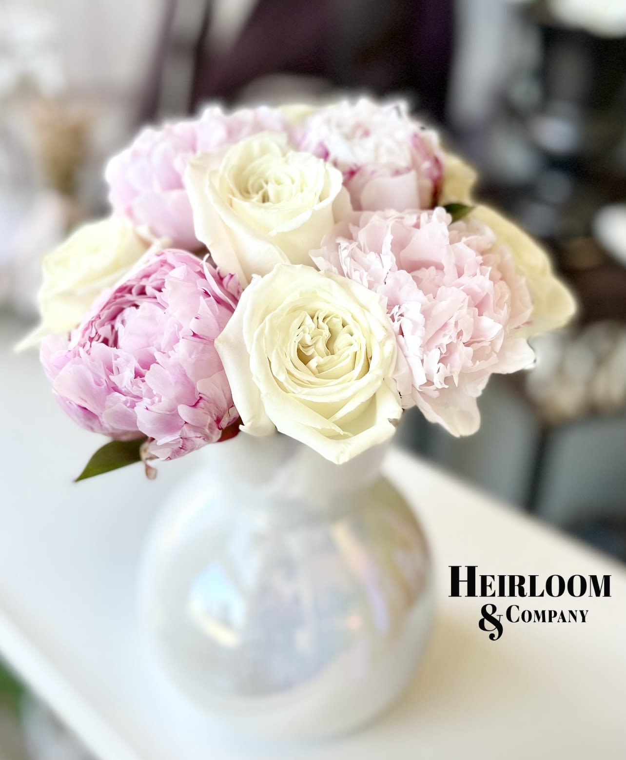 Bouquet of pale pink peonies and cream roses in a white vase