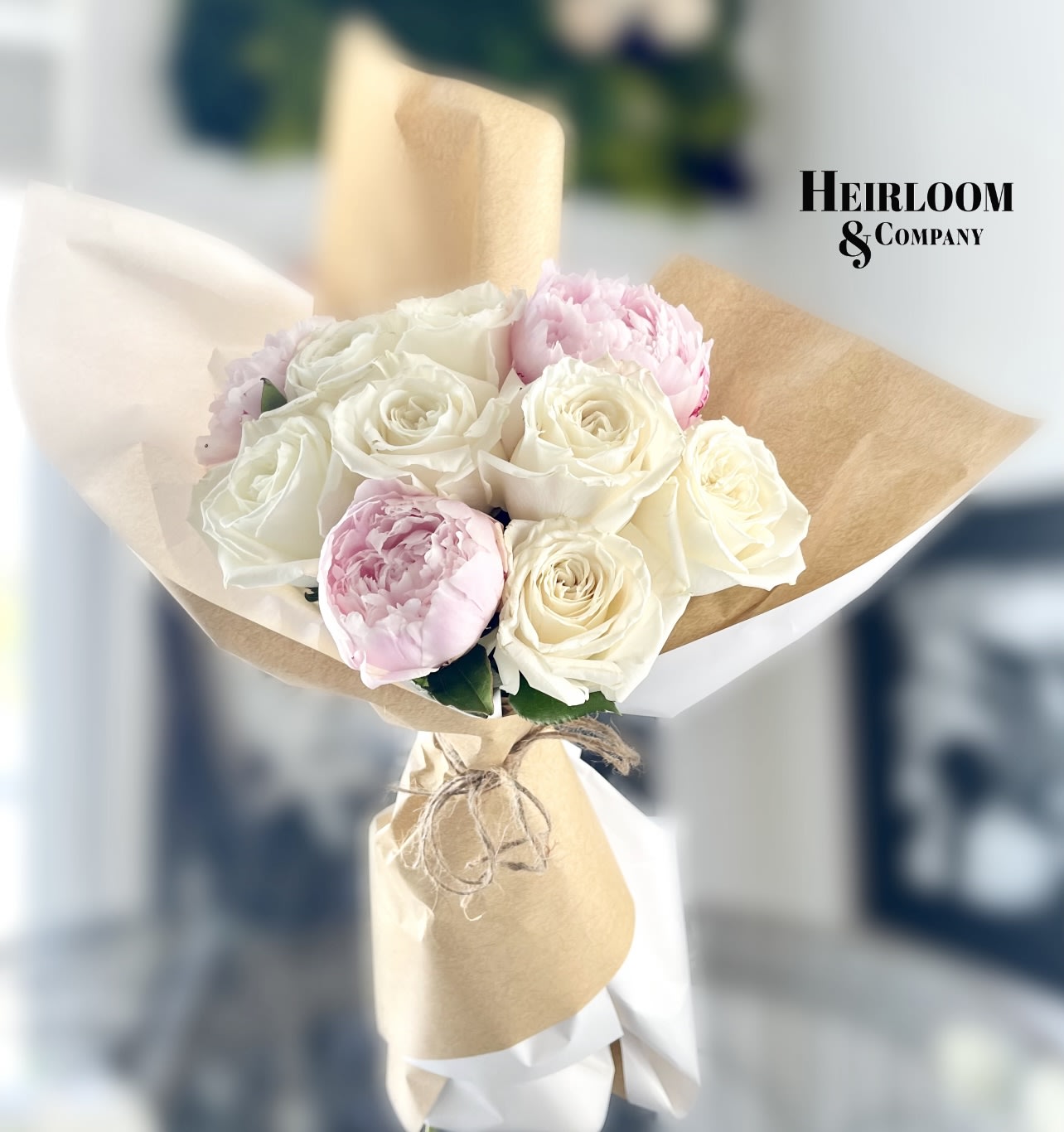 Bouquet of white and pale pink roses wrapped in brown paper