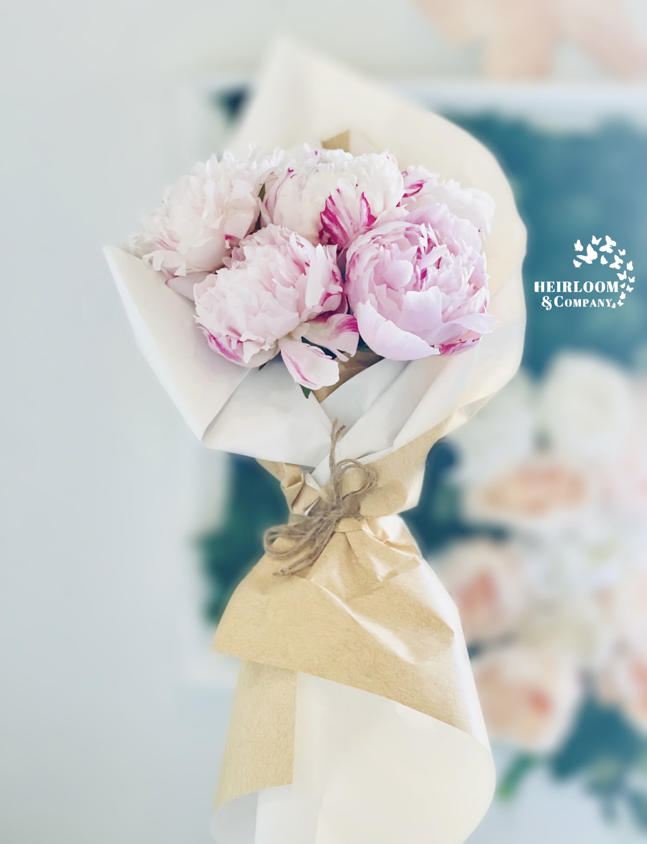 Bouquet of pale pink peonies wrapped in white and kraft paper