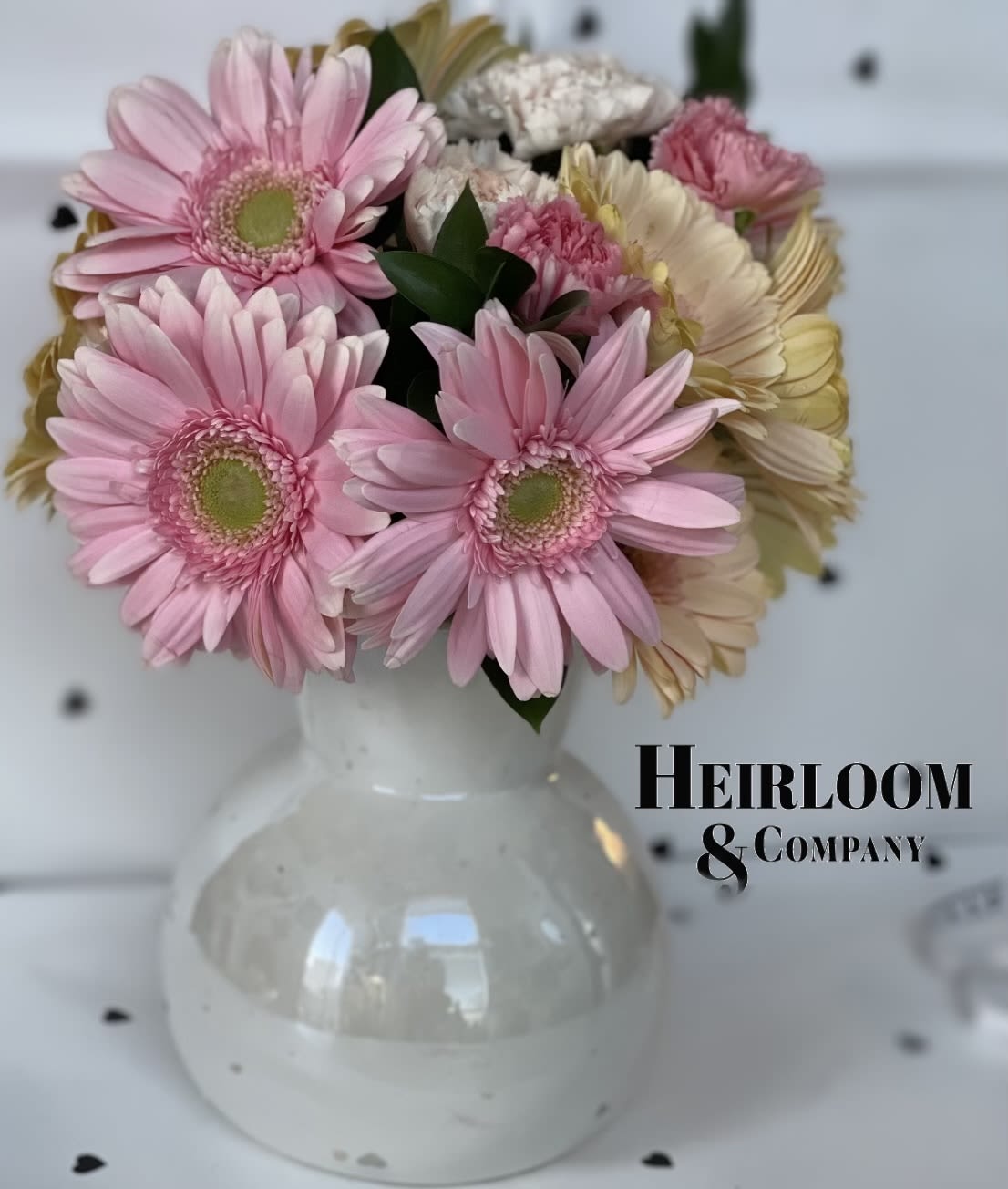 Pink gerbera daisies and carnations arranged in a white vase