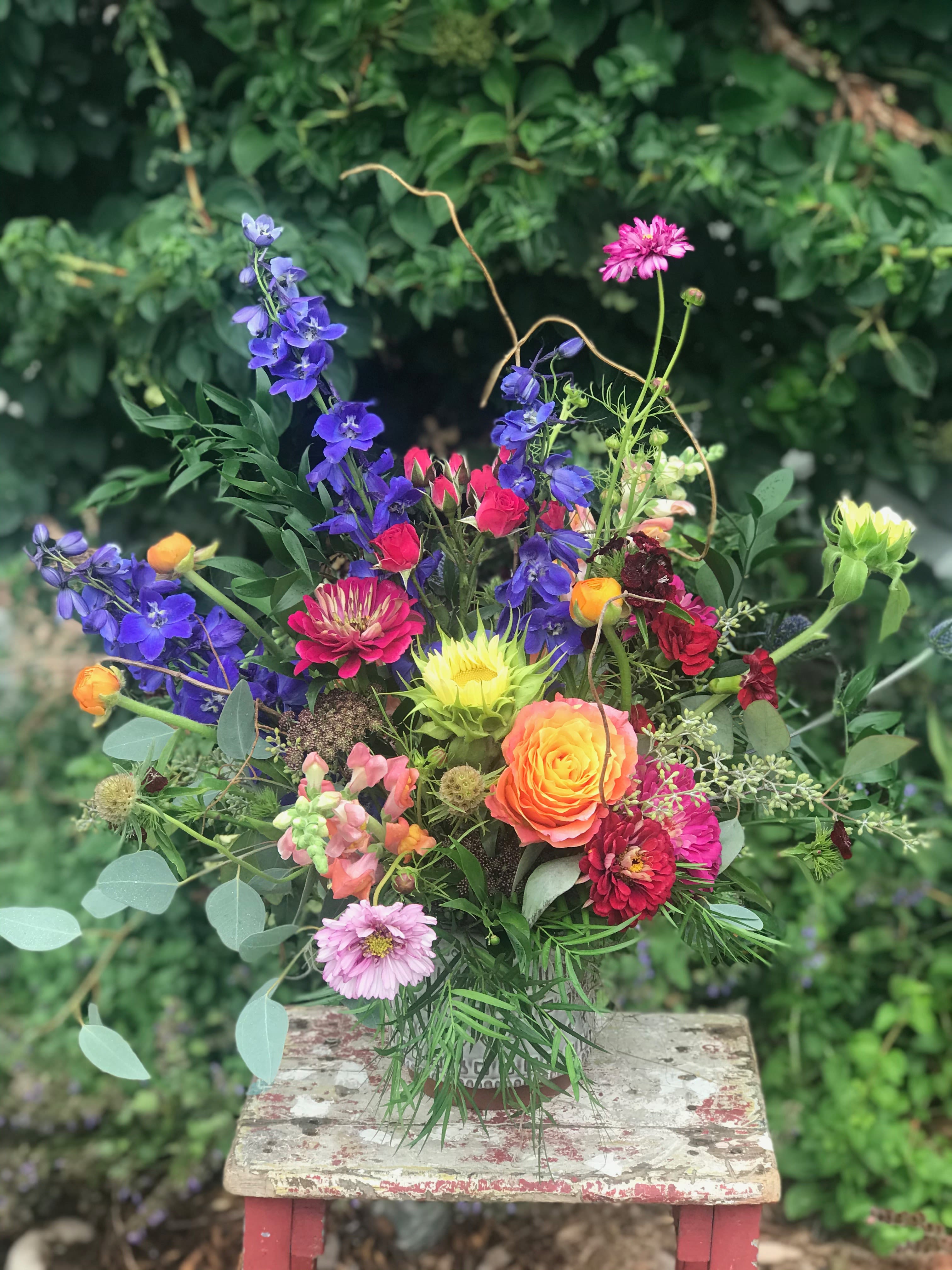 Mixed bouquet with bright blue, pink, orange, and yellow flowers in a vase