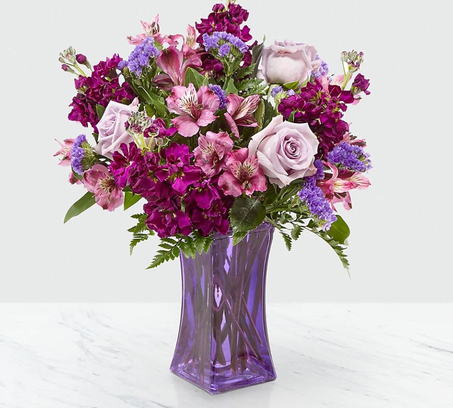Purple Presence™ Bouquet - The Purple Presence™ Bouquet creates a bold splash of color upon arrival, creating a gift of floral style and design your special recipient will always remember. Weaving together lavender roses, purple stock, lavender Peruvian Lilies, purple statice, and lush greens, this flower bouquet exhibits levels of texture and color that will make them take notice. Presented in a modern purple glass vase to give this flower arrangement a finished look, this gift of flowers is ready to express your warmest wishes for a birthday, as a thank you, or as a way to let them know how much you care. GOOD bouquet is approximately 14"H x 11"W. BETTER bouquet is approximately 15"H x 12"W. BEST bouquet is approximately 17"H x 14"W.  