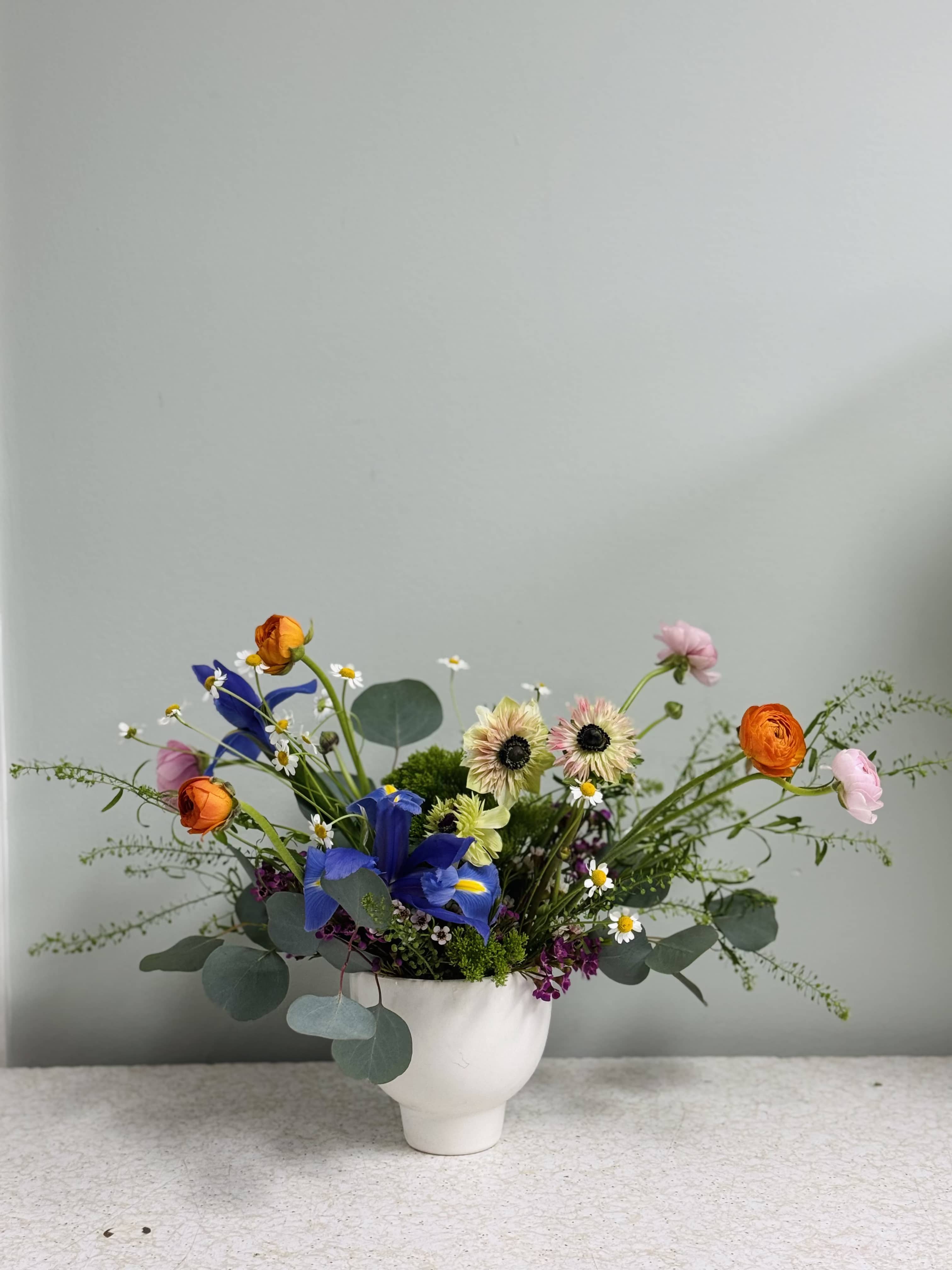 Mixed bouquet in a white vase with blue and orange blooms