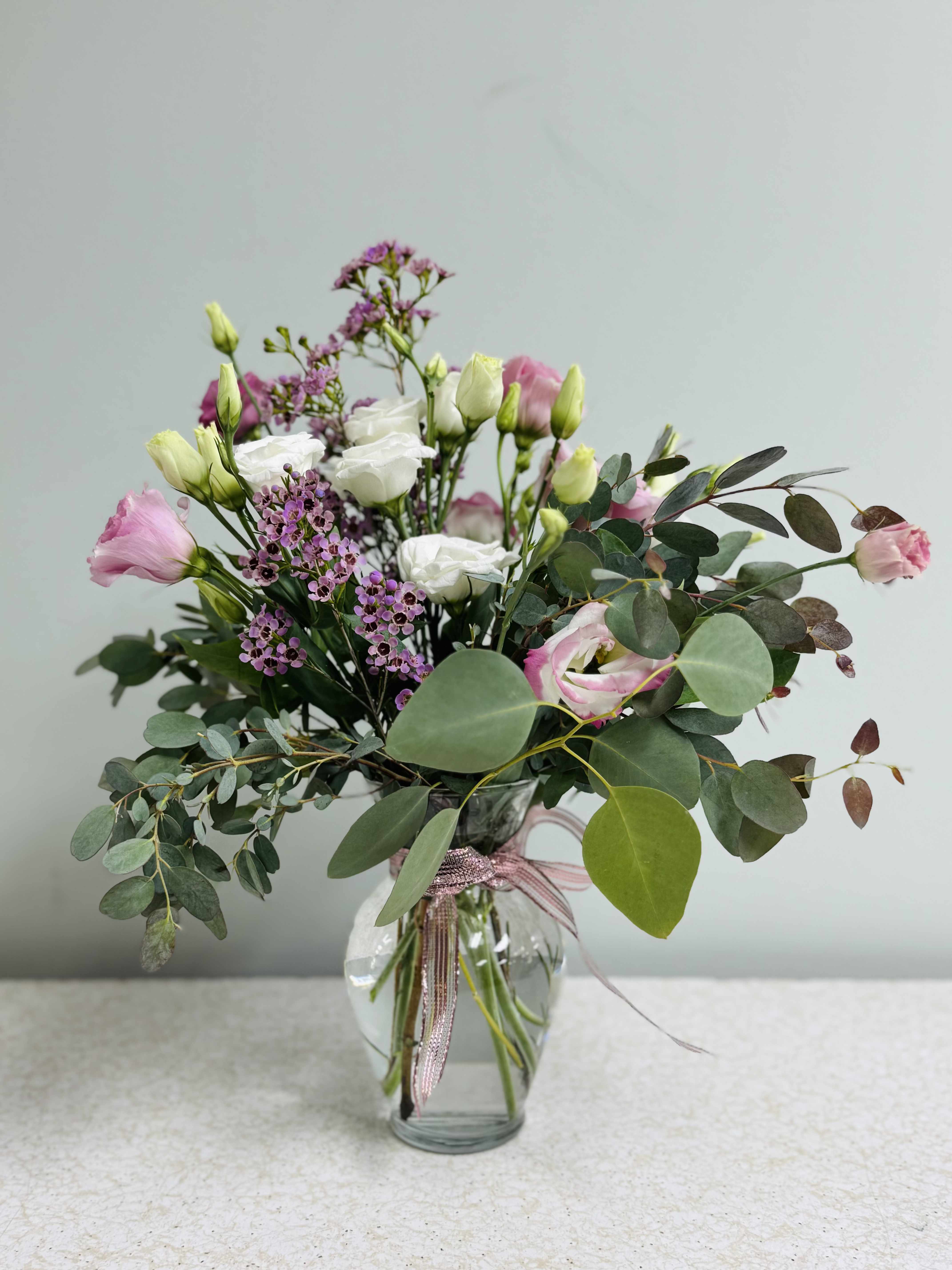 Pink and white bouquet in a clear glass vase with eucalyptus