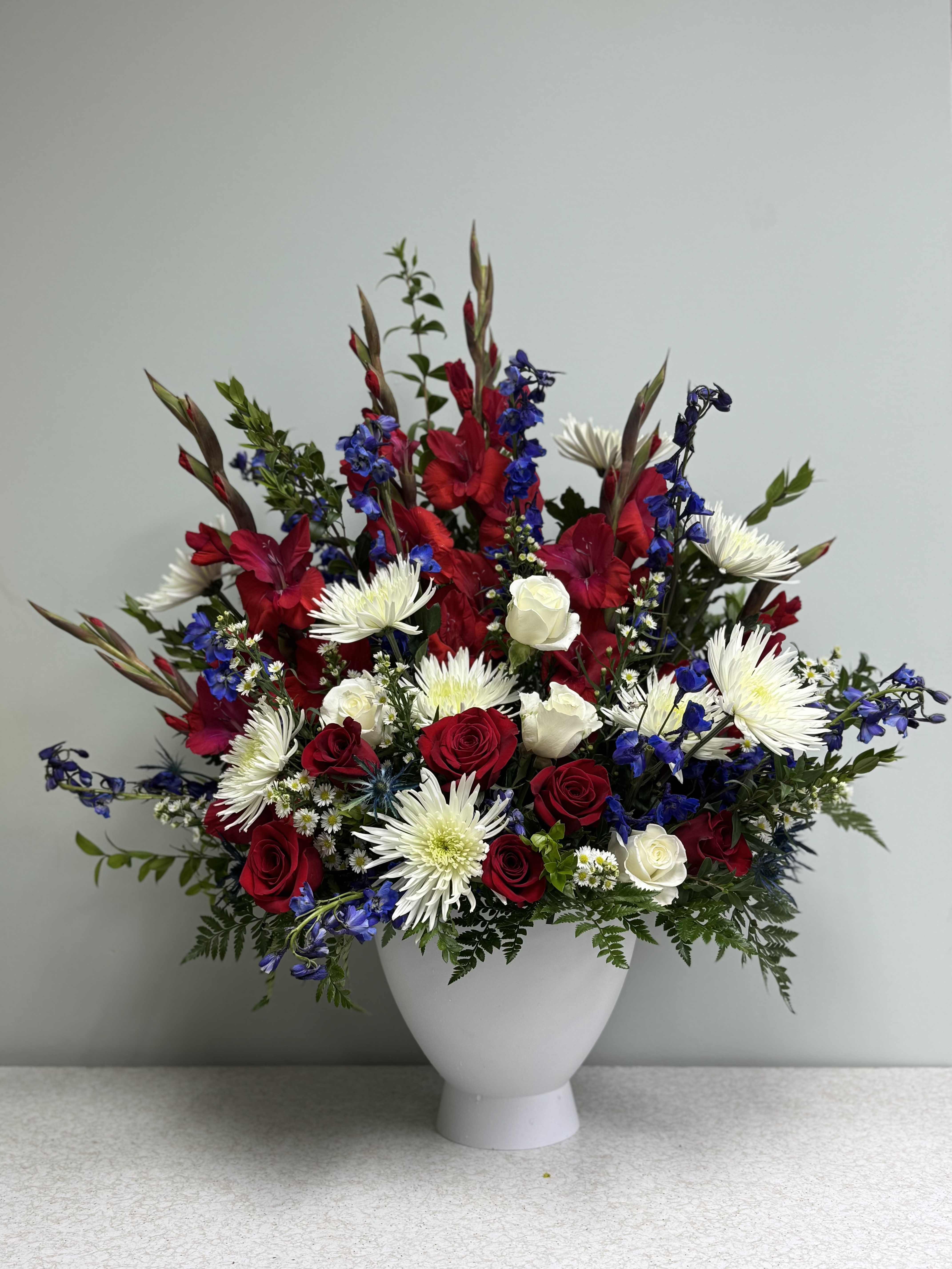 Red and white roses with white daisies in a white vase
