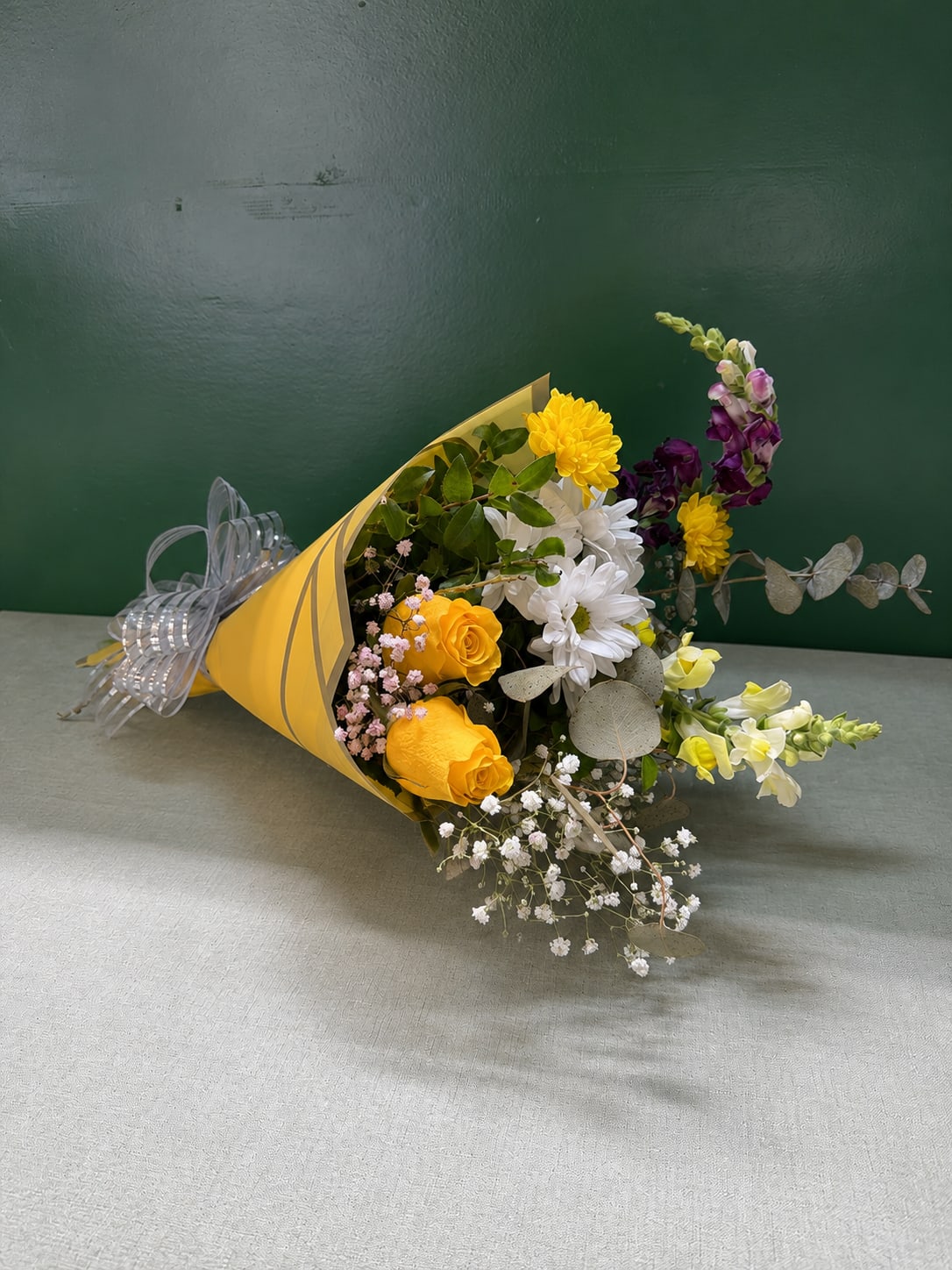 Bouquet of yellow, white, and purple flowers wrapped in yellow paper
