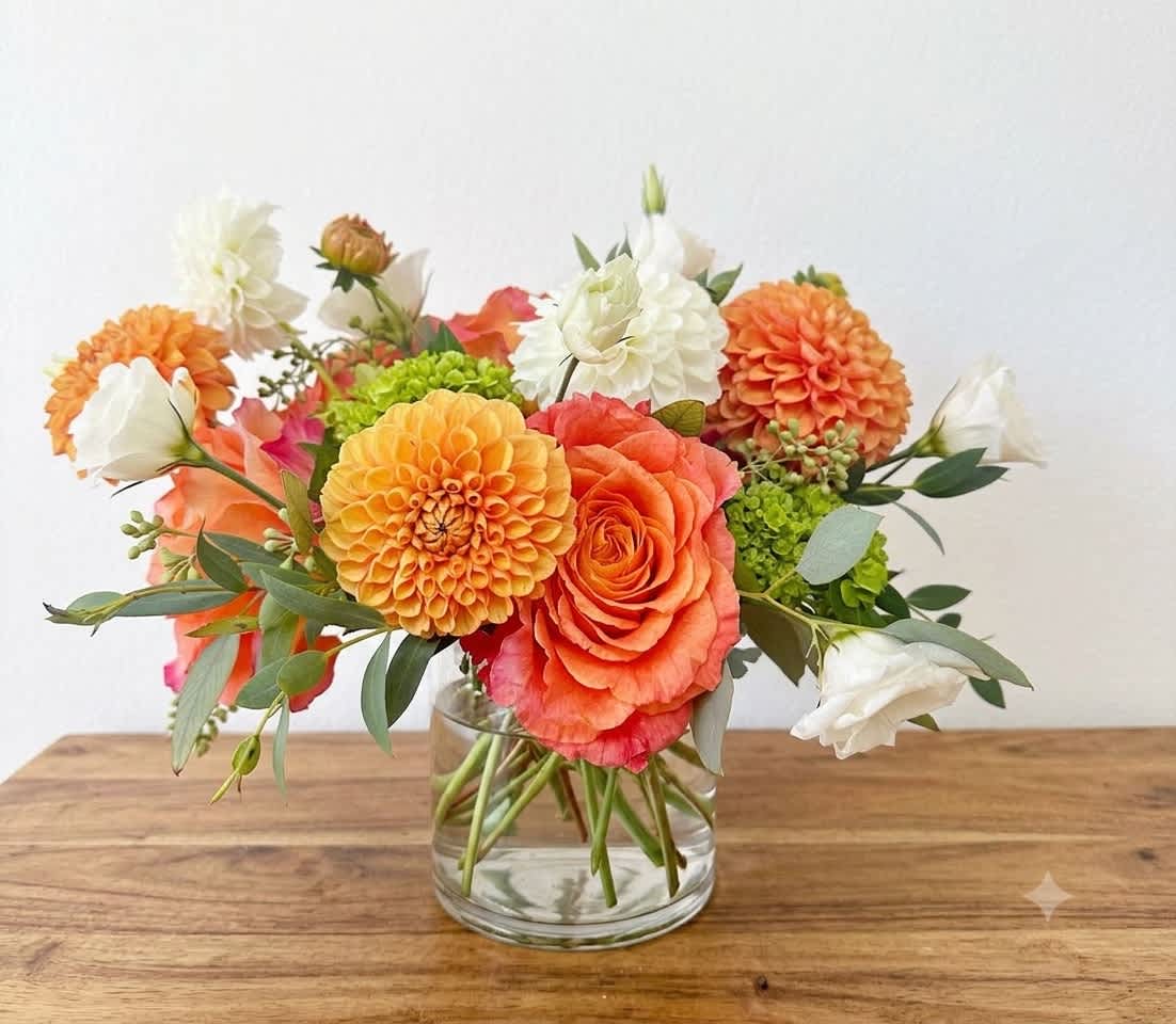 Orange and white flower arrangement in a clear glass vase